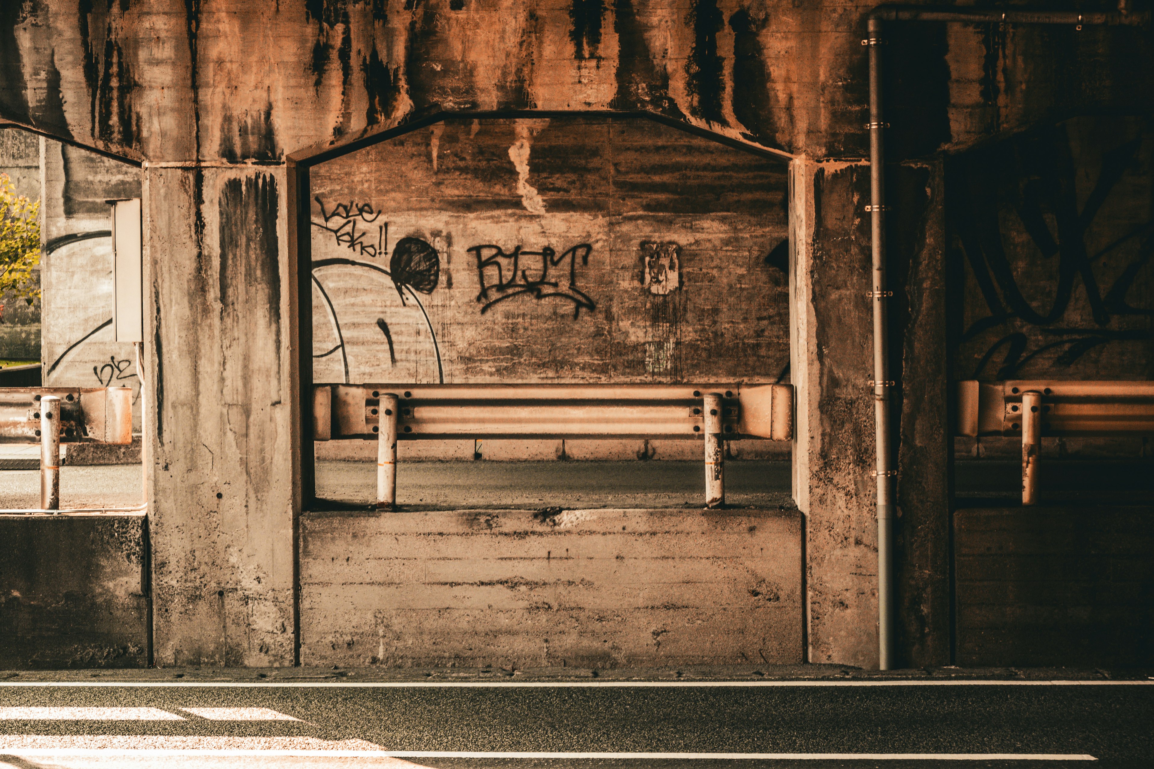 Photo of an underpass featuring graffiti on concrete walls and a concrete bench