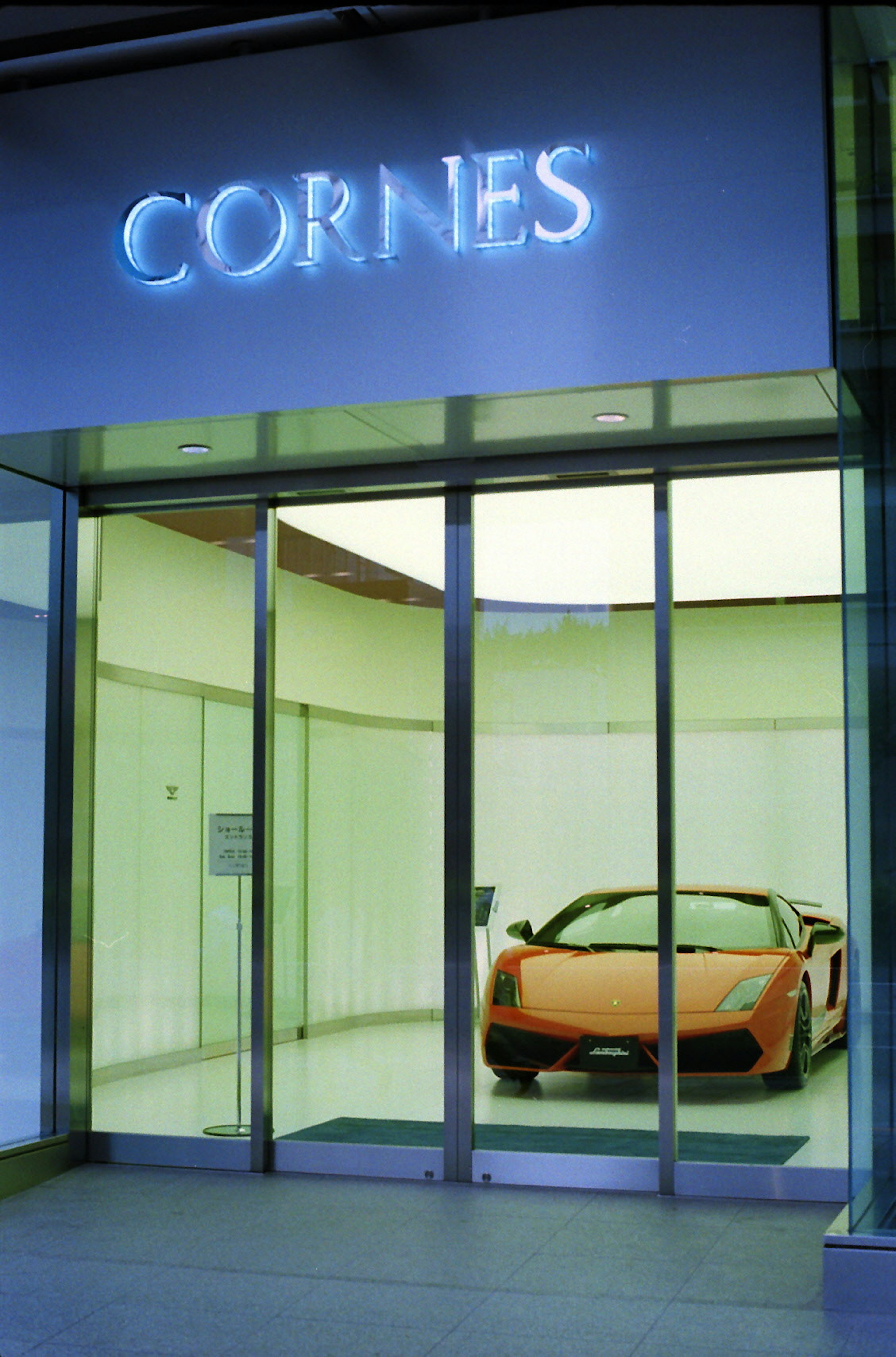 Showroom featuring an orange Lamborghini behind glass doors