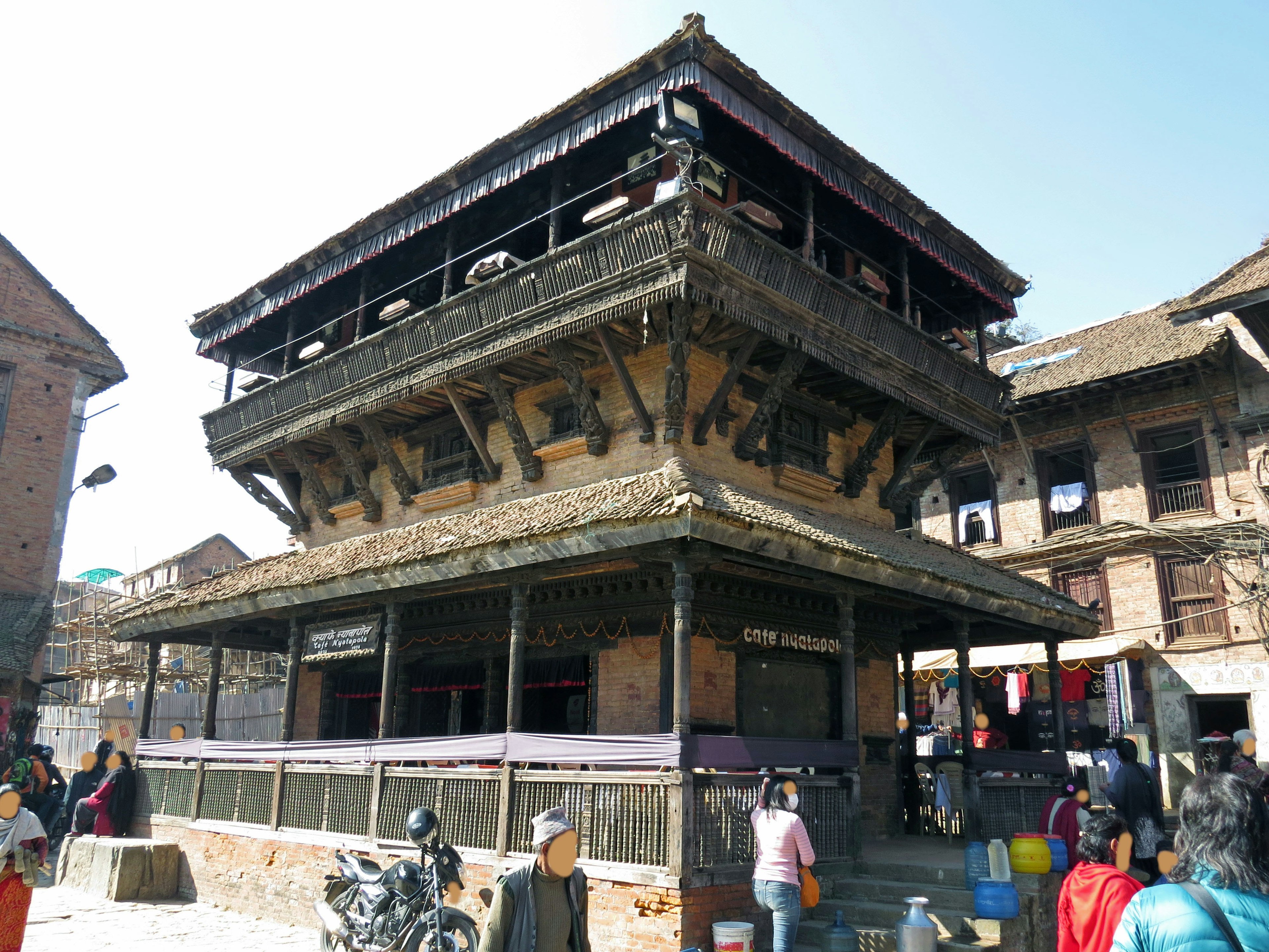 Architecture traditionnelle en bois d'un temple népalais donnant sur une rue animée