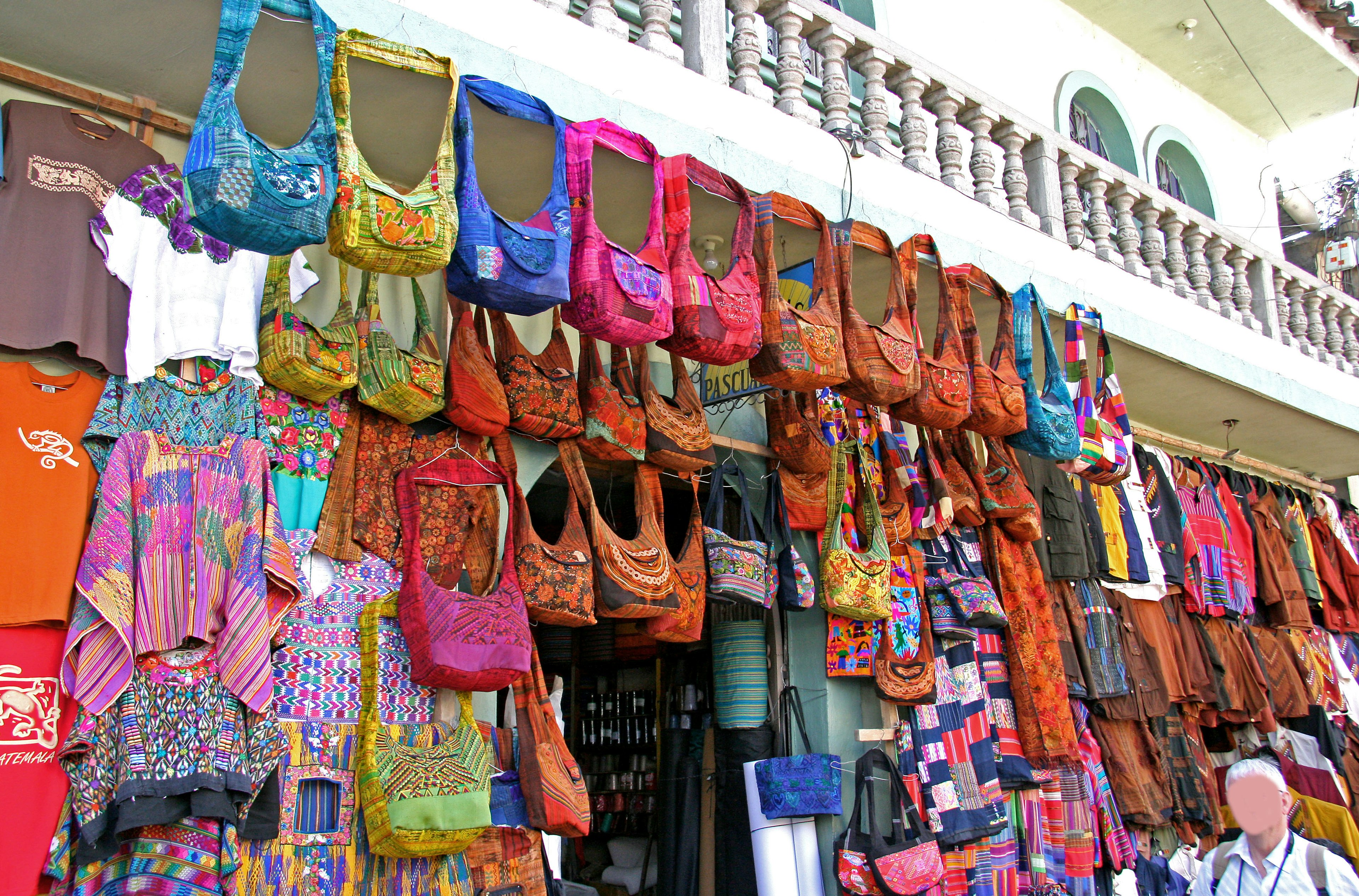 Bolsas coloridas exhibidas en una pared de mercado