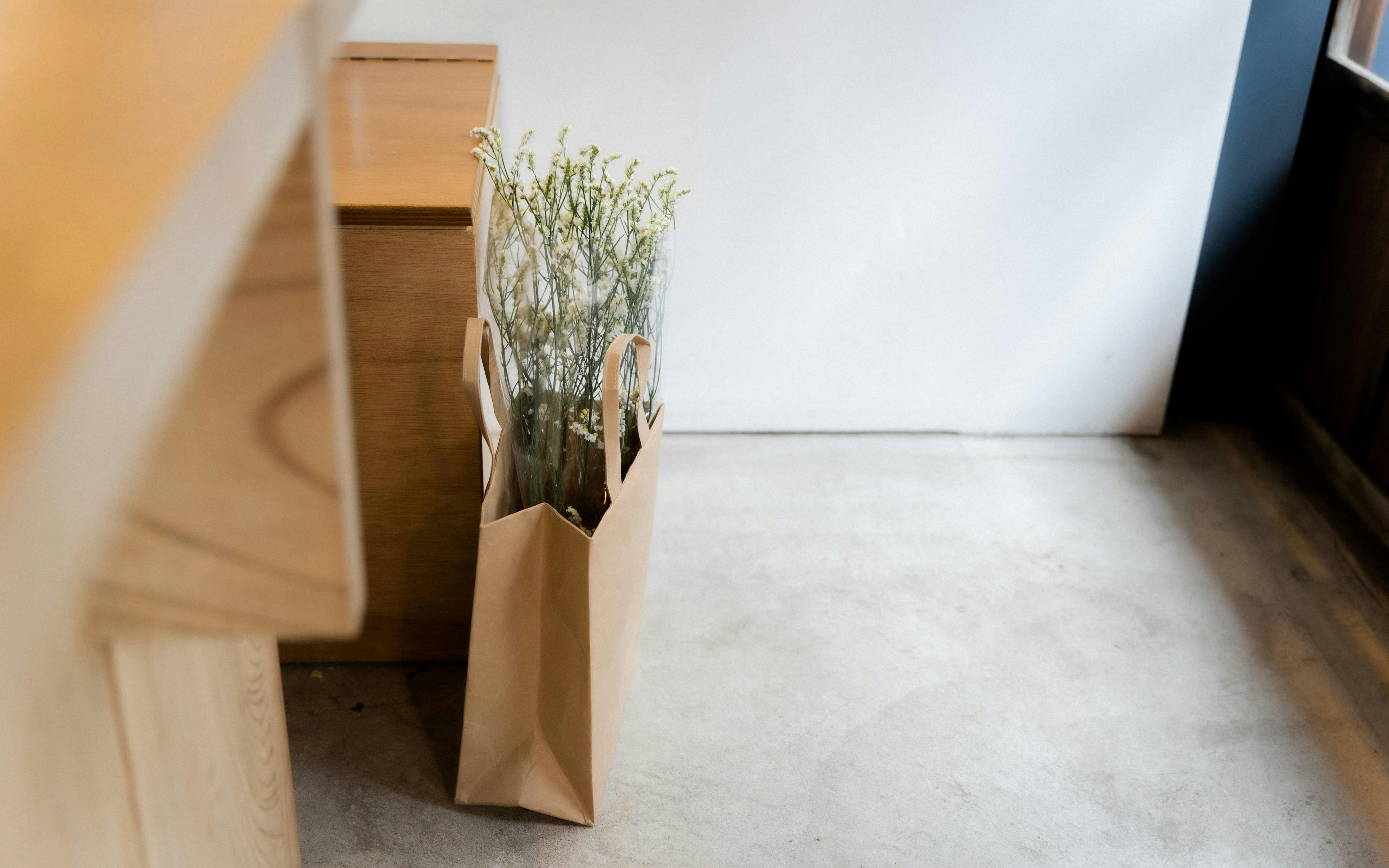 Eine braune Papiertüte mit Blumen darin in einem ruhigen Innenraum