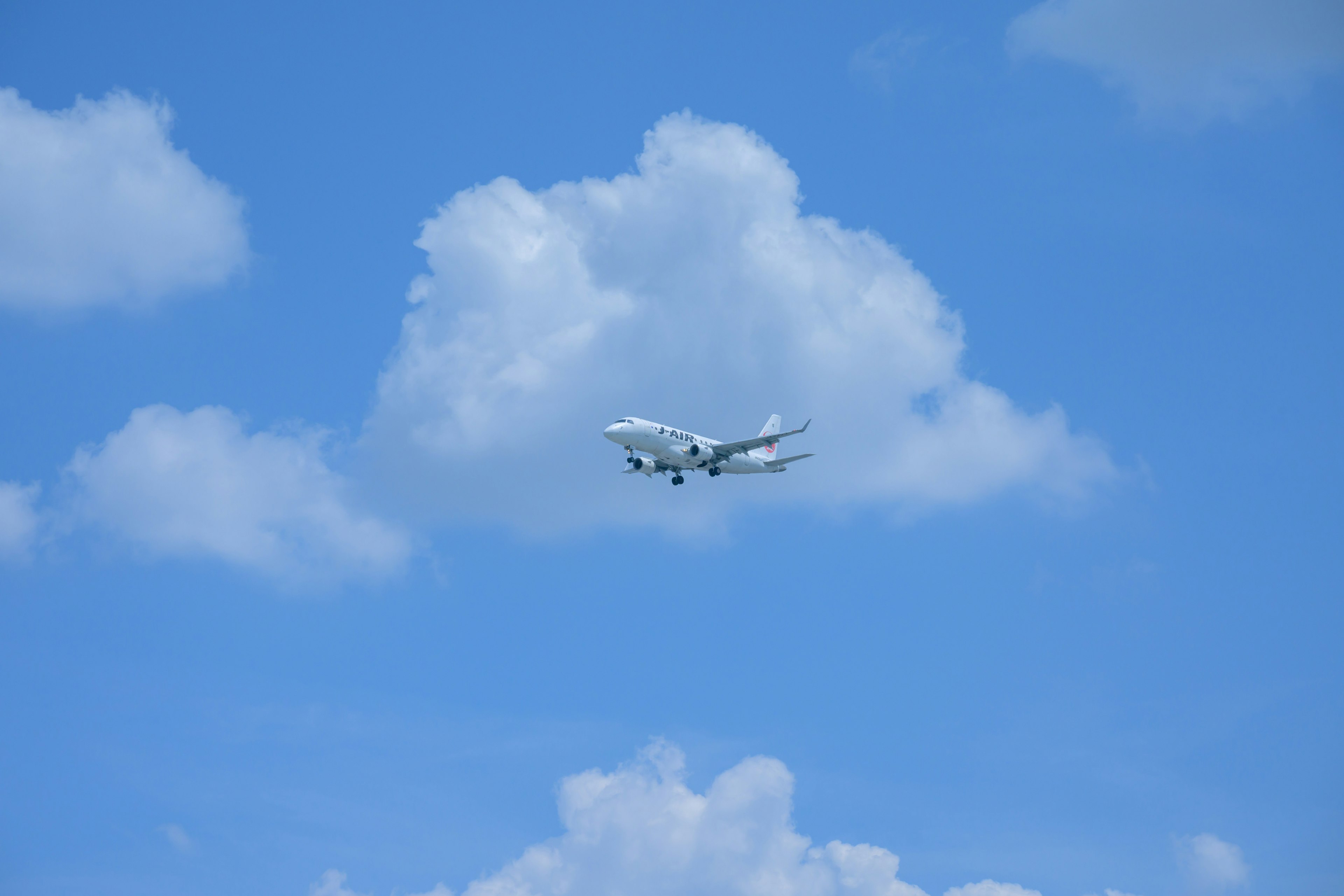 Aereo che vola in un cielo blu con nuvole bianche soffici