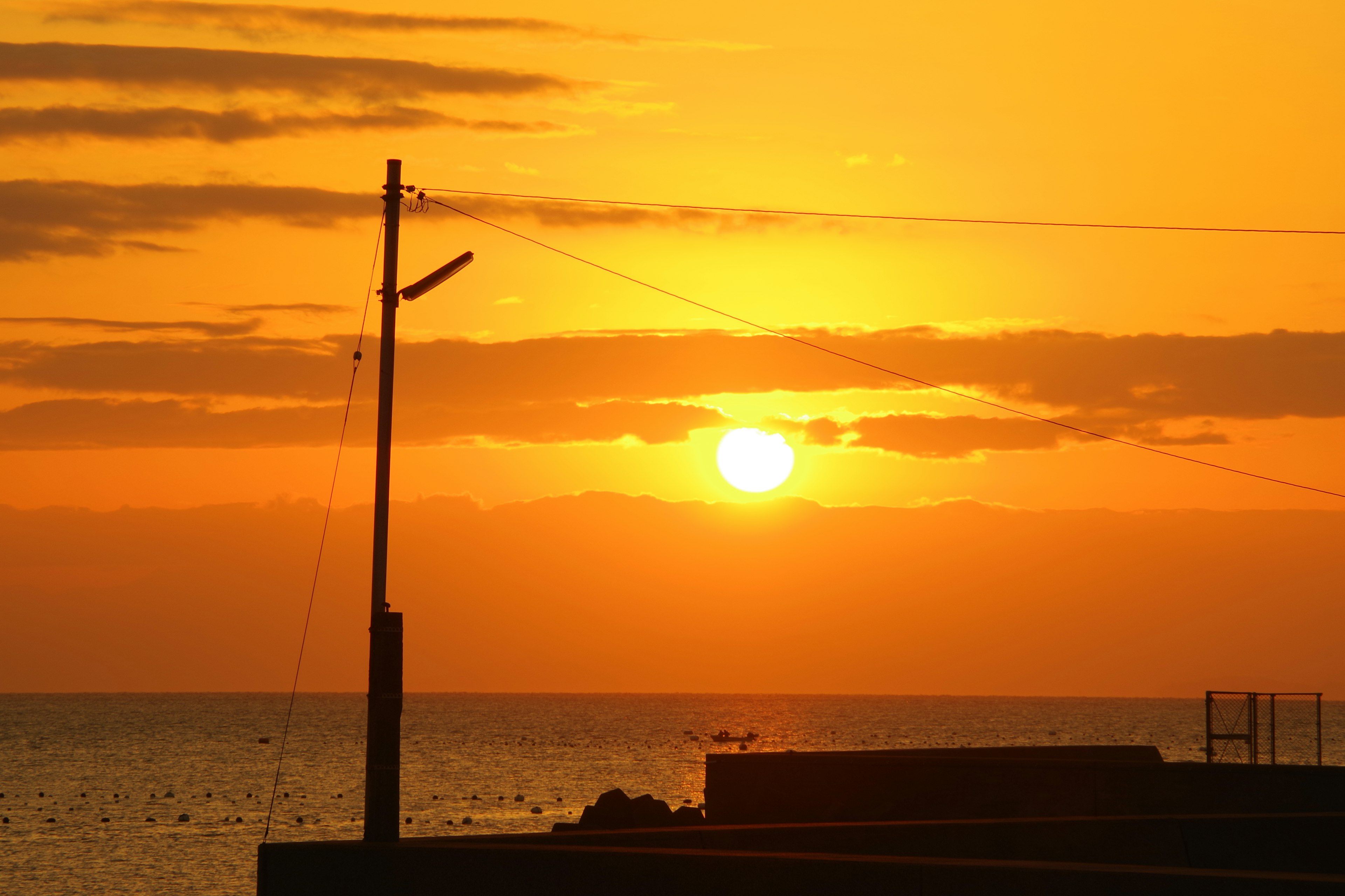 Bellissimo tramonto arancione sul mare con la silhouette di un lampione