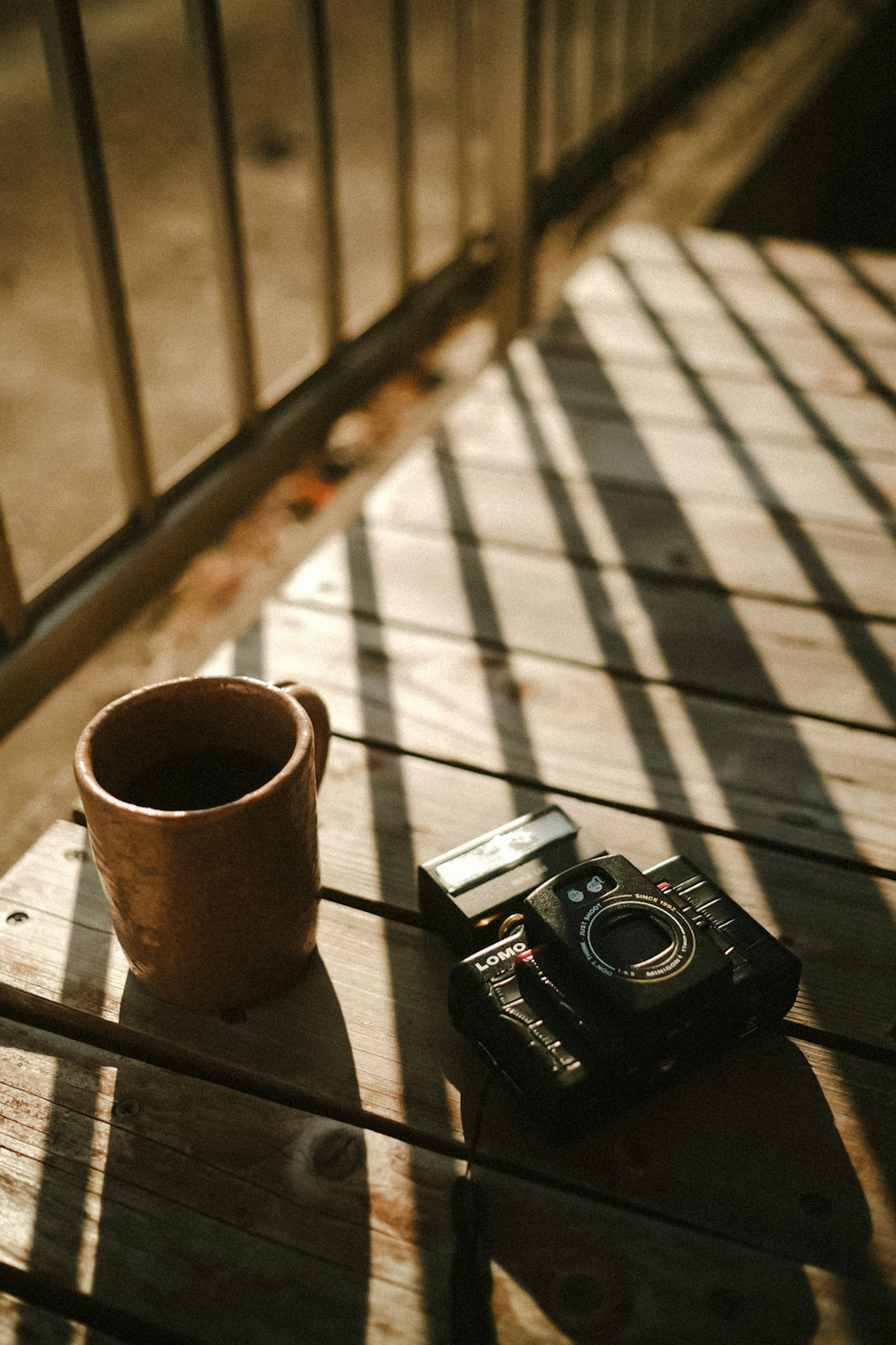 Image of a camera and a ceramic cup on a wooden table