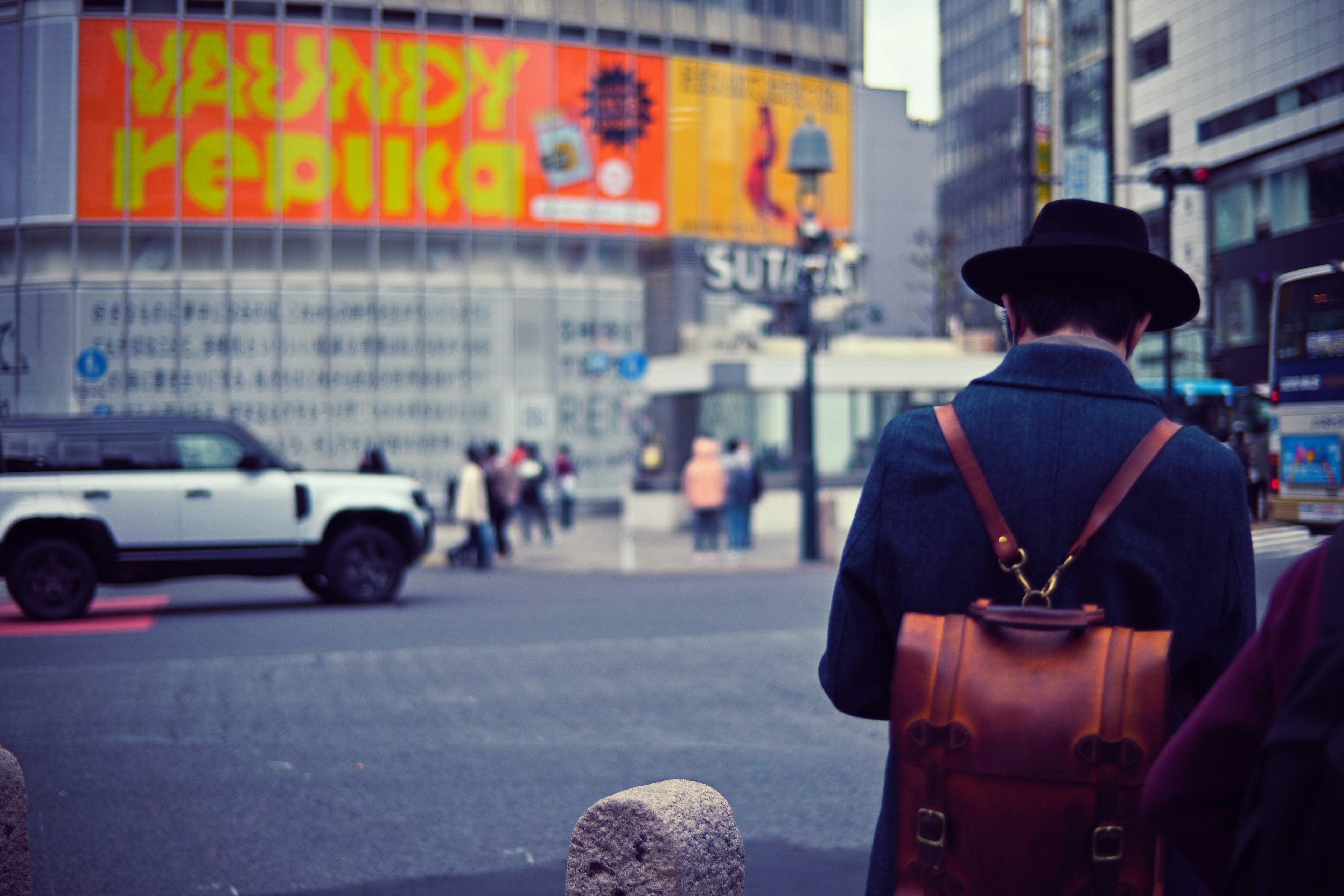 A person walking in the street with a colorful advertisement in the background