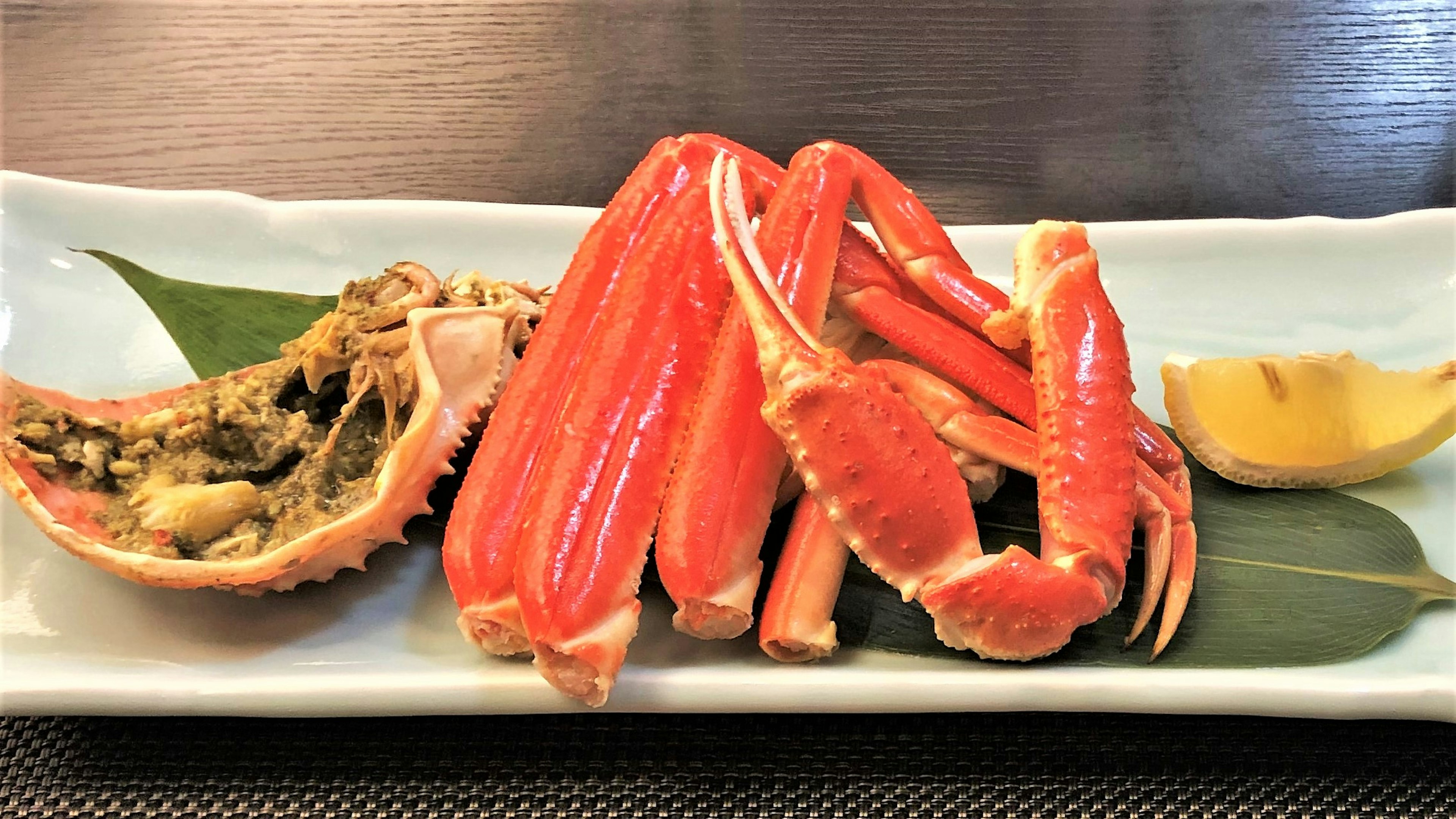 A plate featuring red crab legs and meat garnished with lemon and leaves