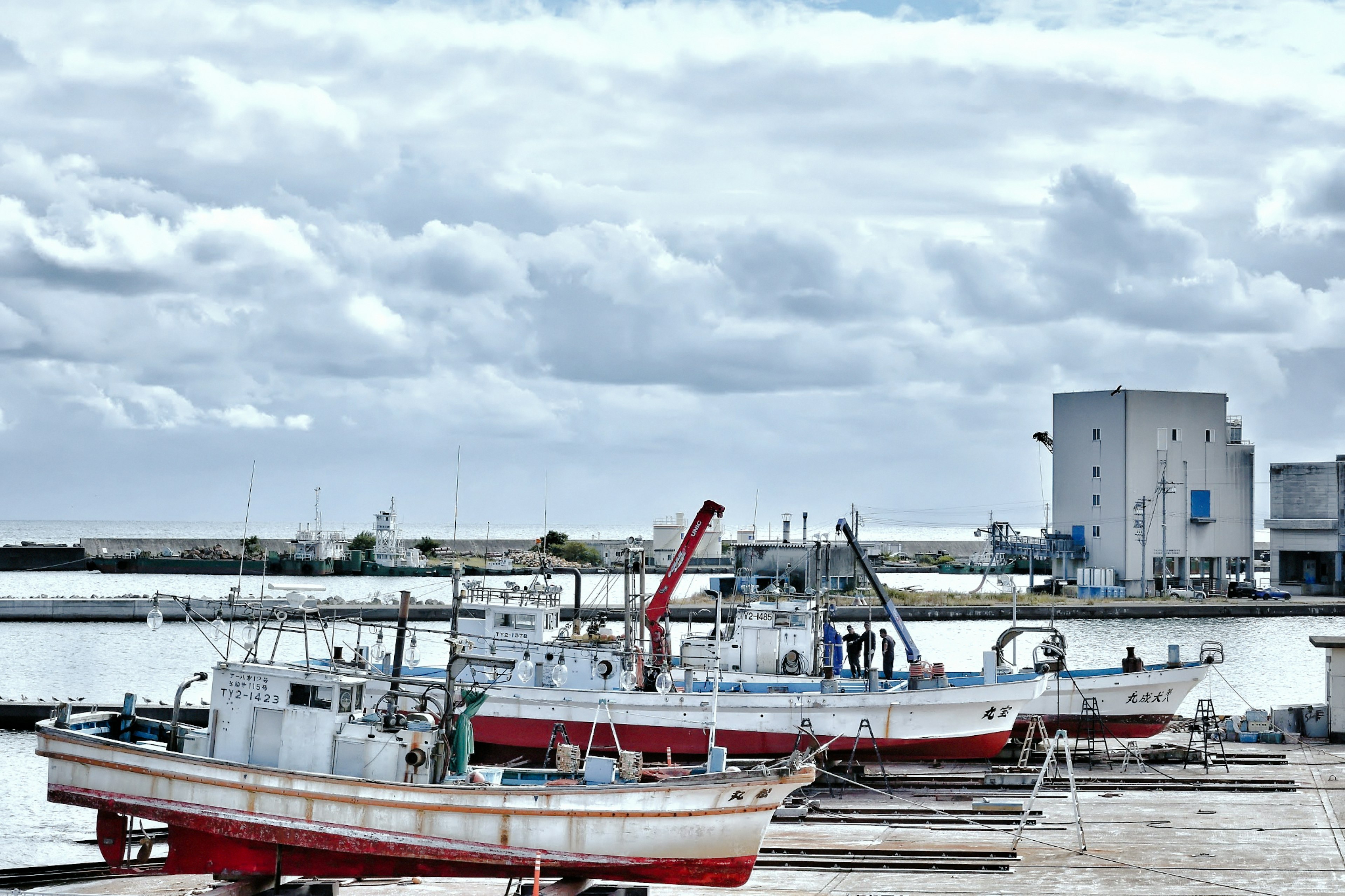 Barcos de pesca atracados junto al mar bajo un cielo nublado