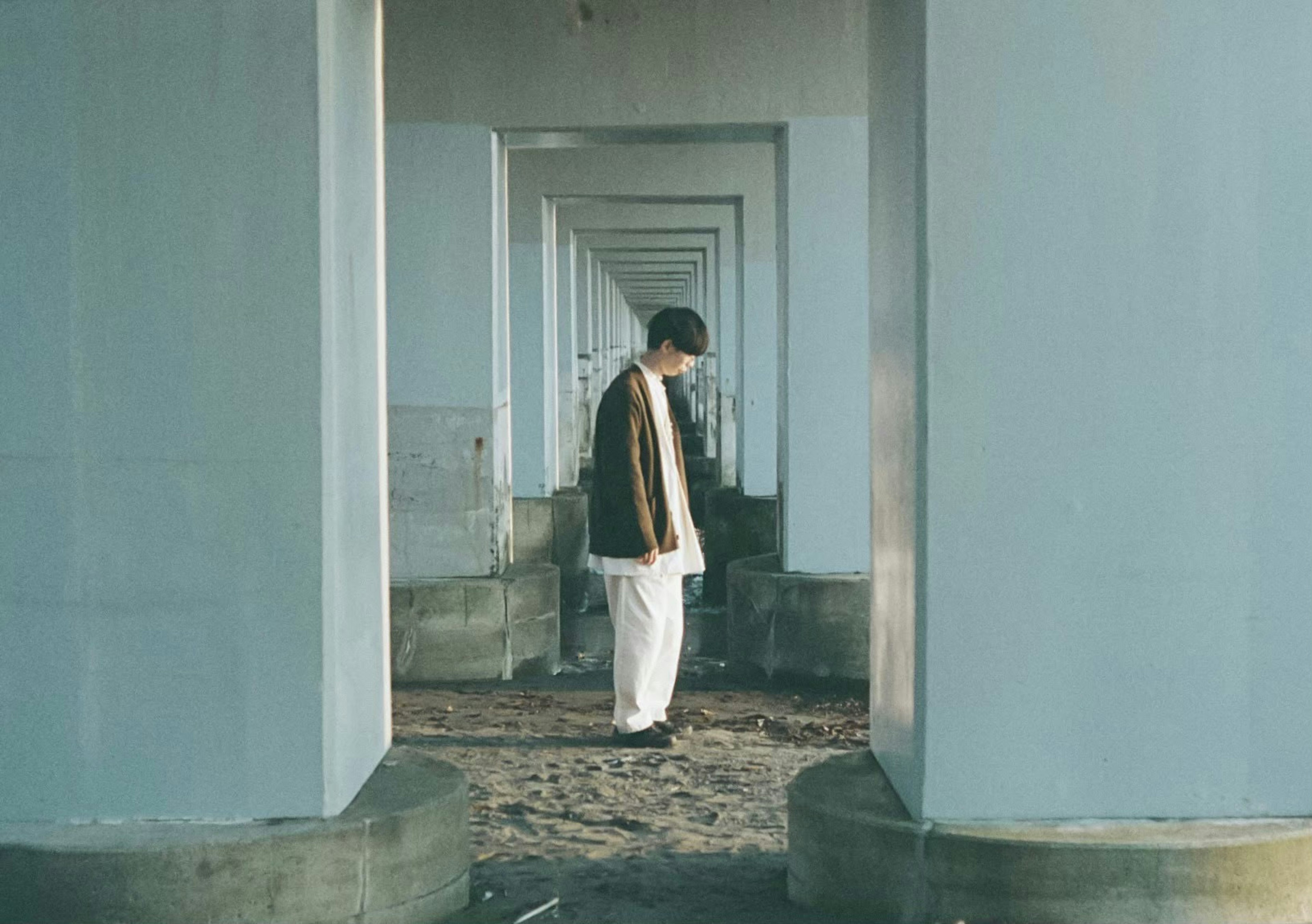 Un homme se tenant entre des piliers bleus montrant un sentiment de solitude dans un environnement calme