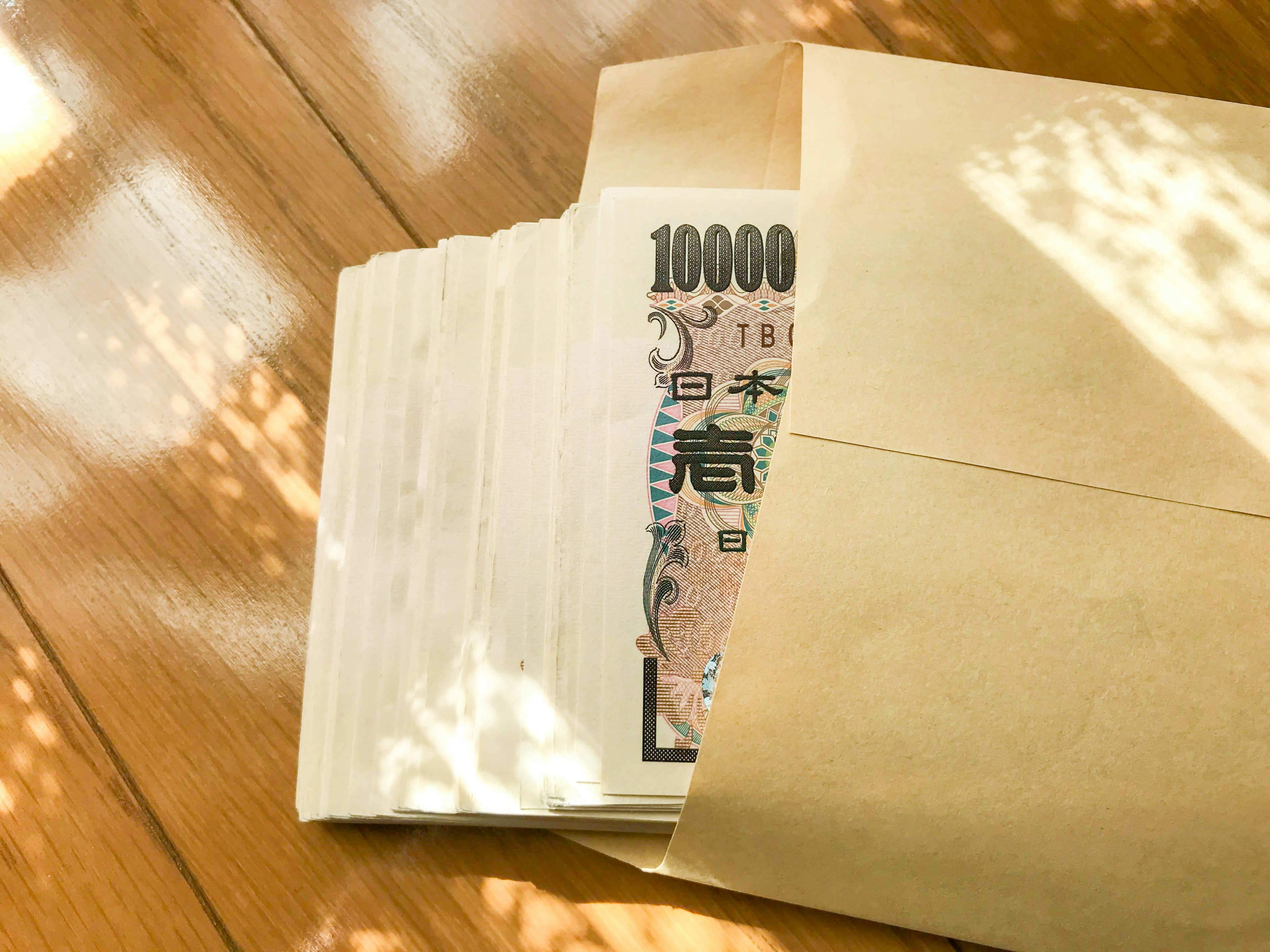 A brown envelope containing Japanese 10,000 yen bills is visible