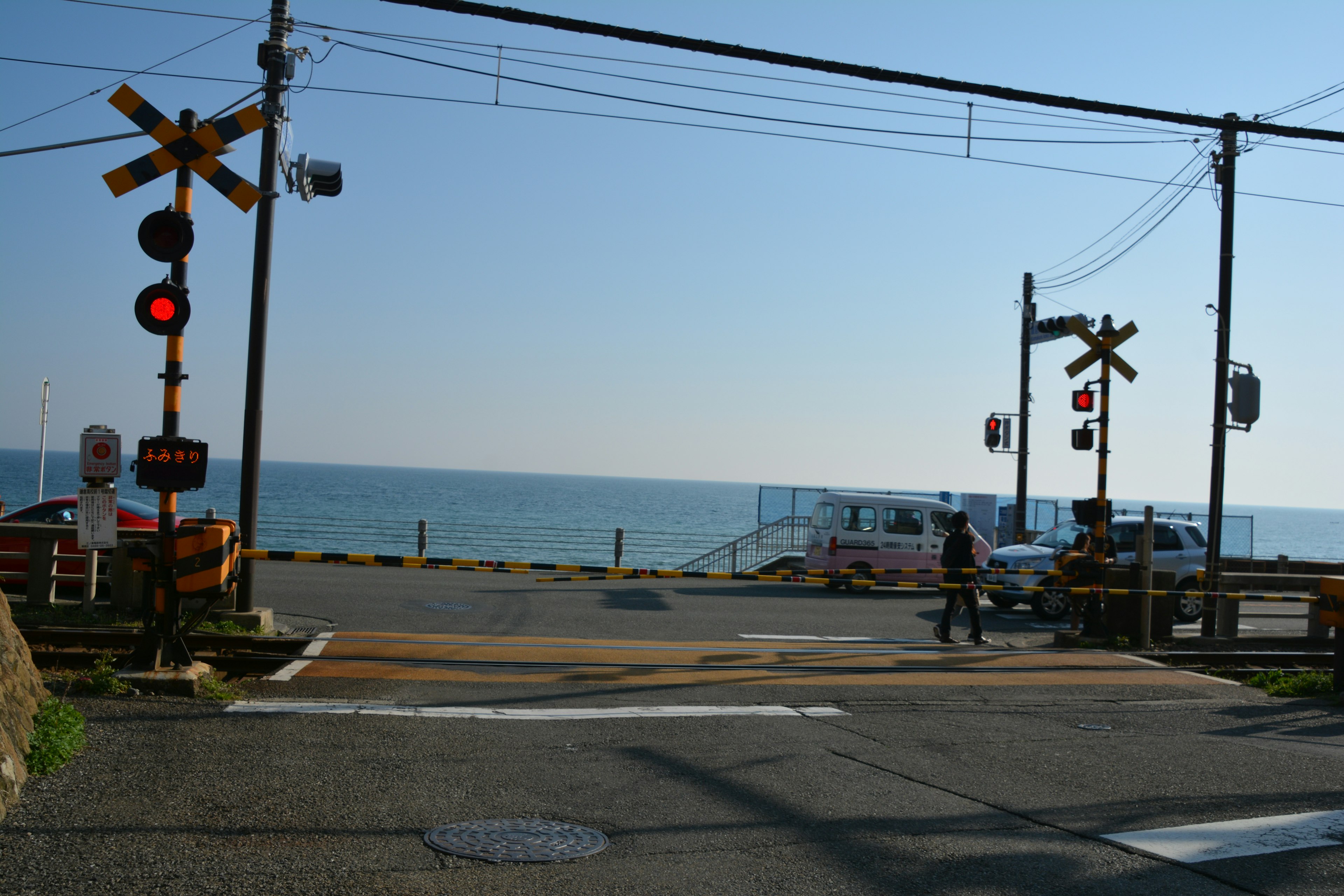 A railway crossing near the sea with a clear blue sky