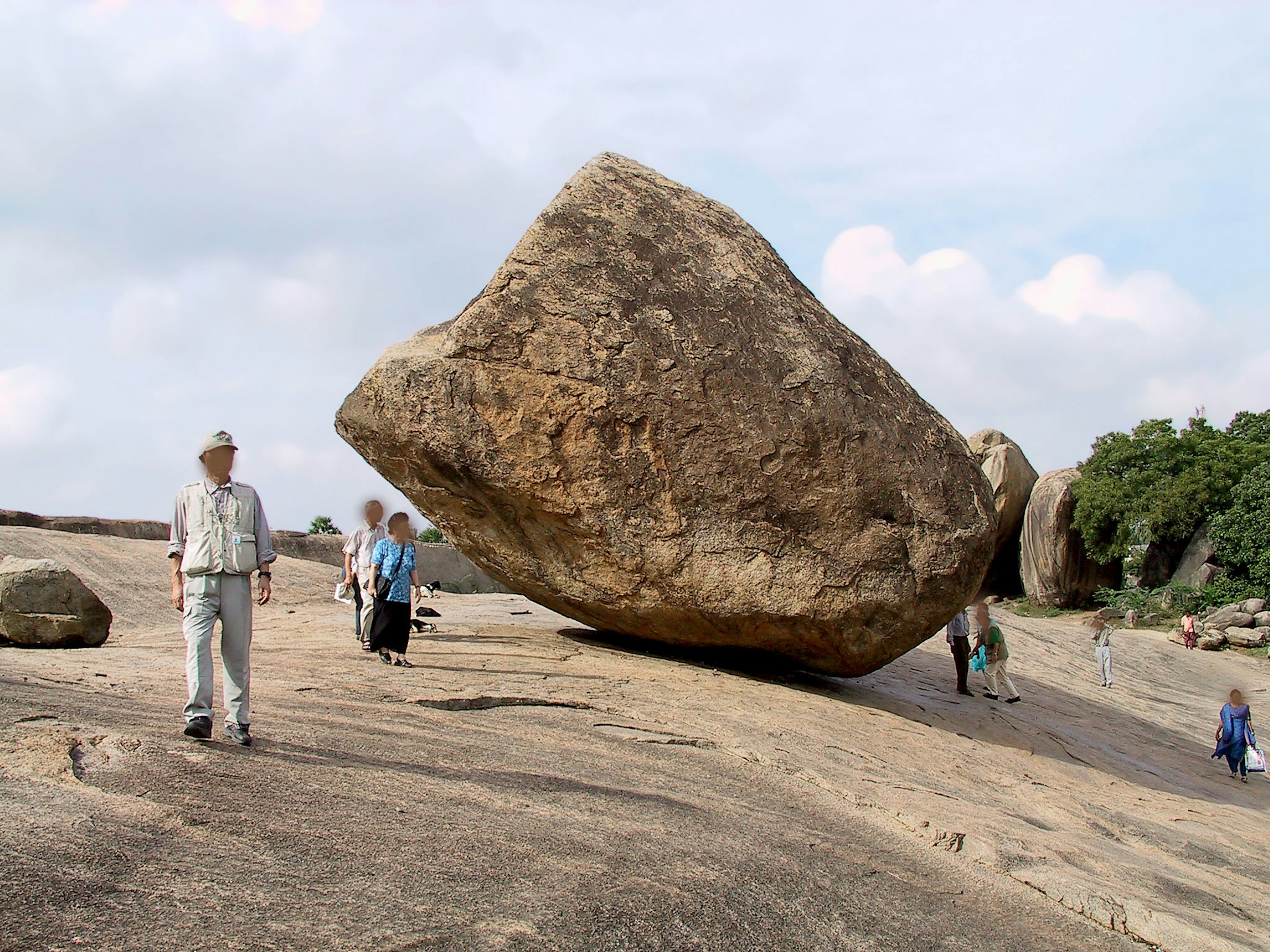 Persone vicino a un grande masso su terreno roccioso