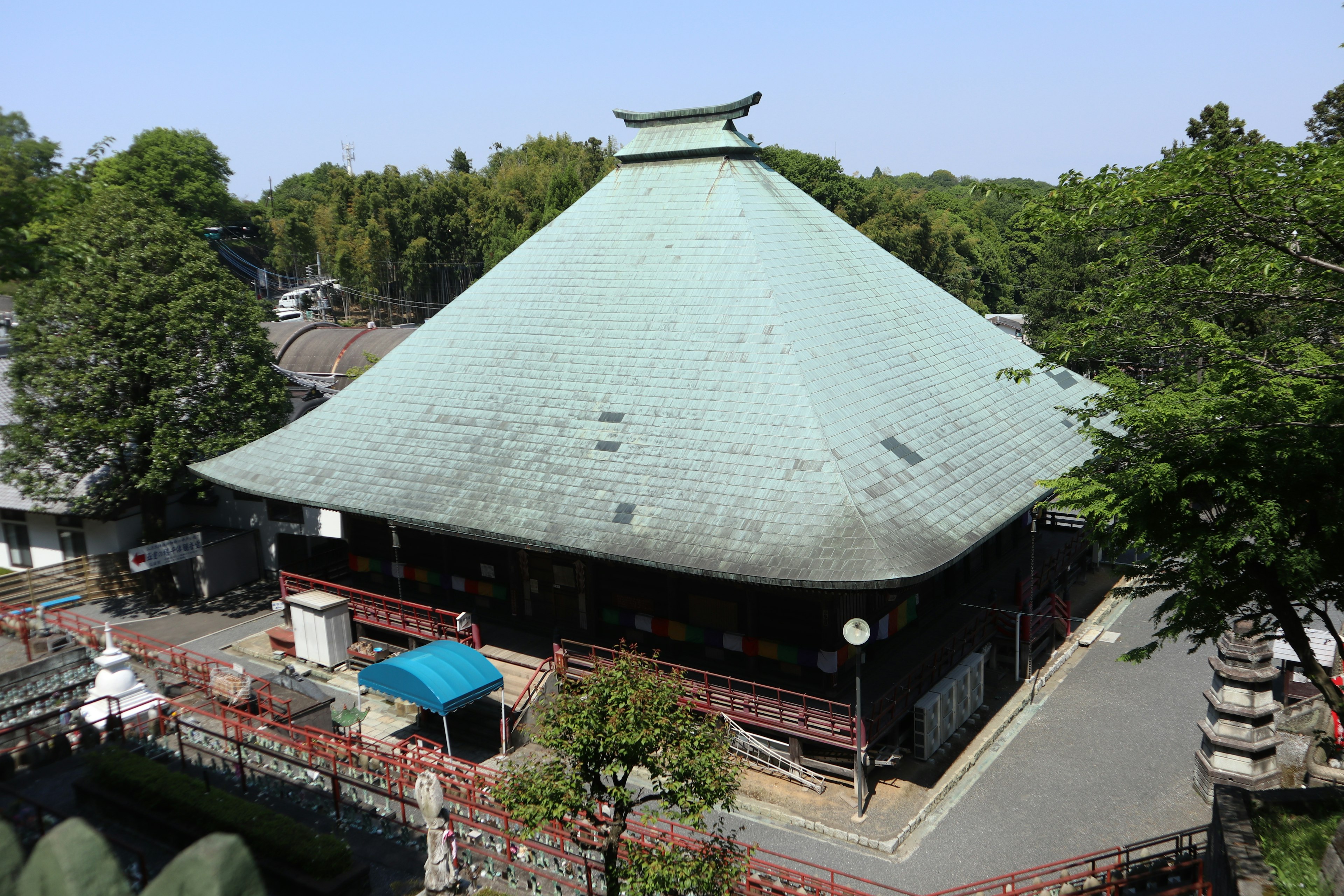 緑に囲まれた伝統的な日本の寺院の屋根は青銅色で広がり、周囲の自然と調和している