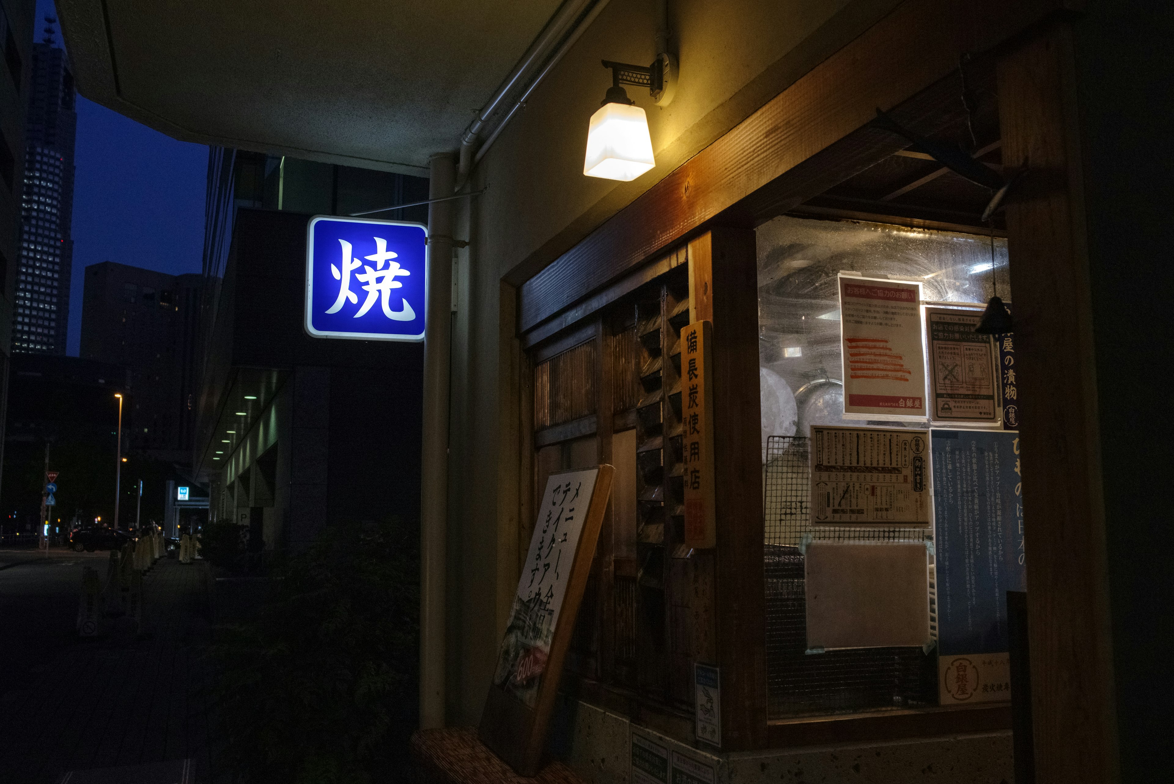 Exterior de un restaurante de comida a la parrilla por la noche Iluminación cálida y entrada de madera