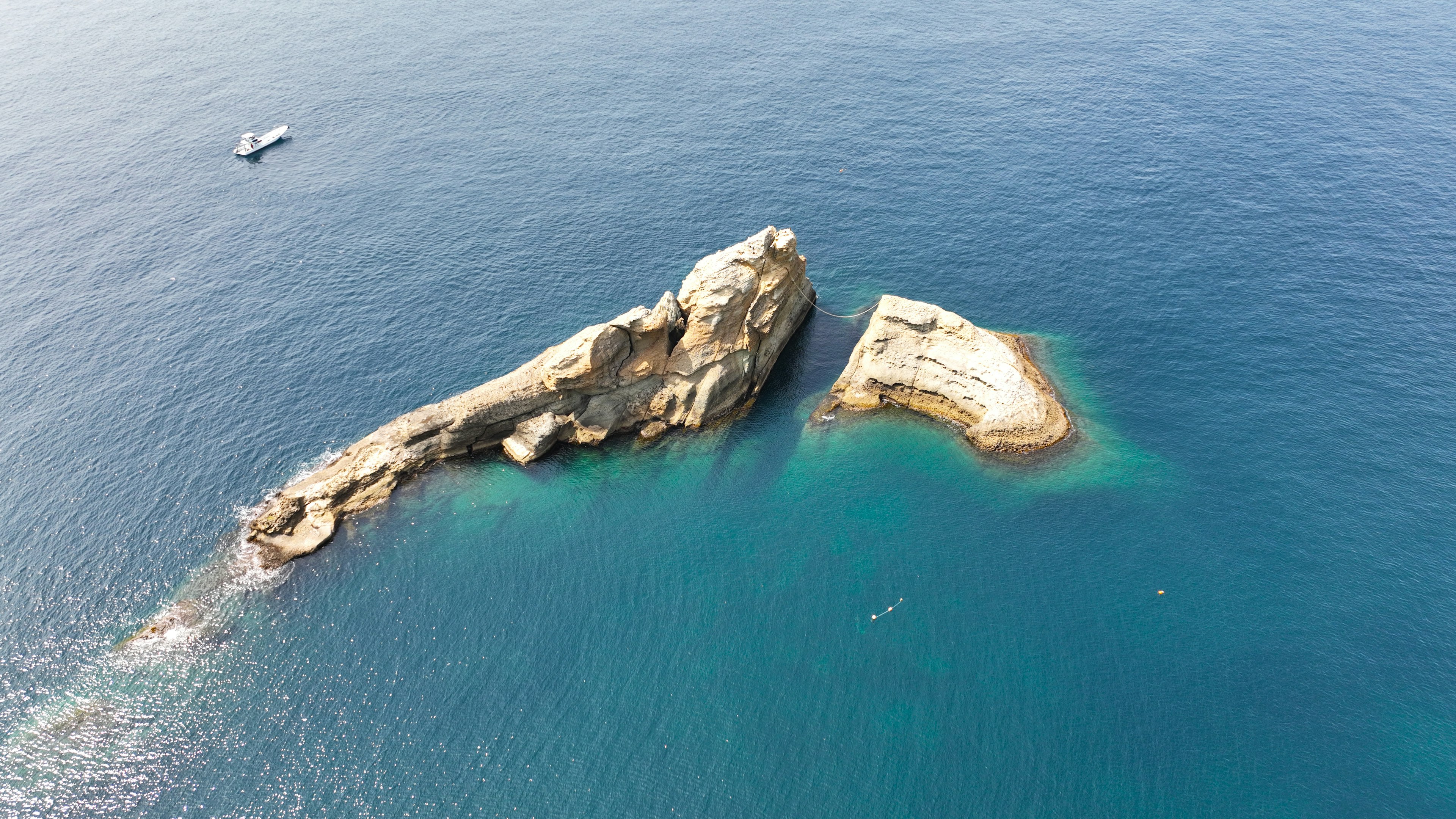 青い海に浮かぶ二つの岩の島と小さなボート