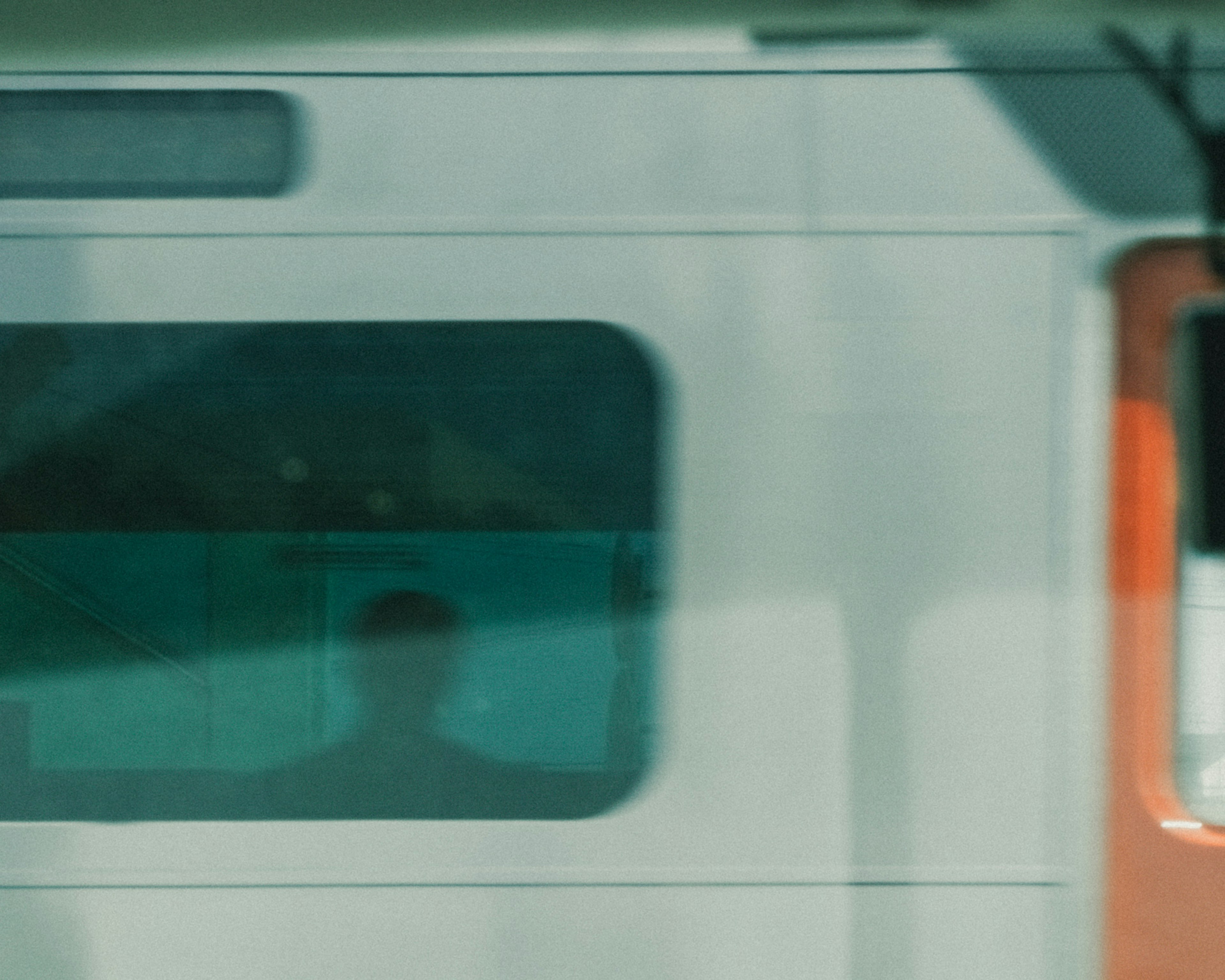 Silhouette of a person seen through a train window with a blend of colors