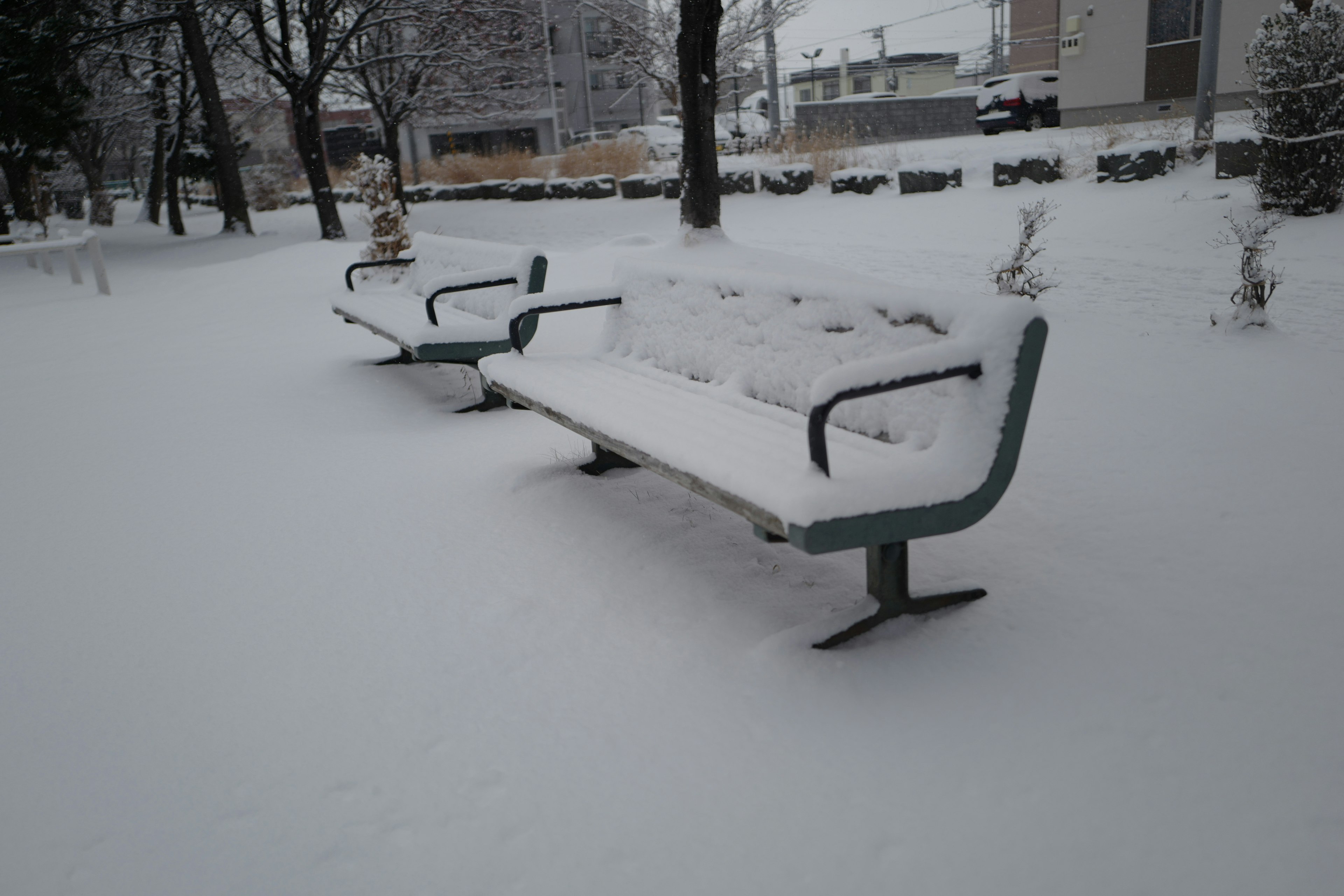 Parkbank, die mit Schnee bedeckt ist, mit einer ruhigen Winterlandschaft