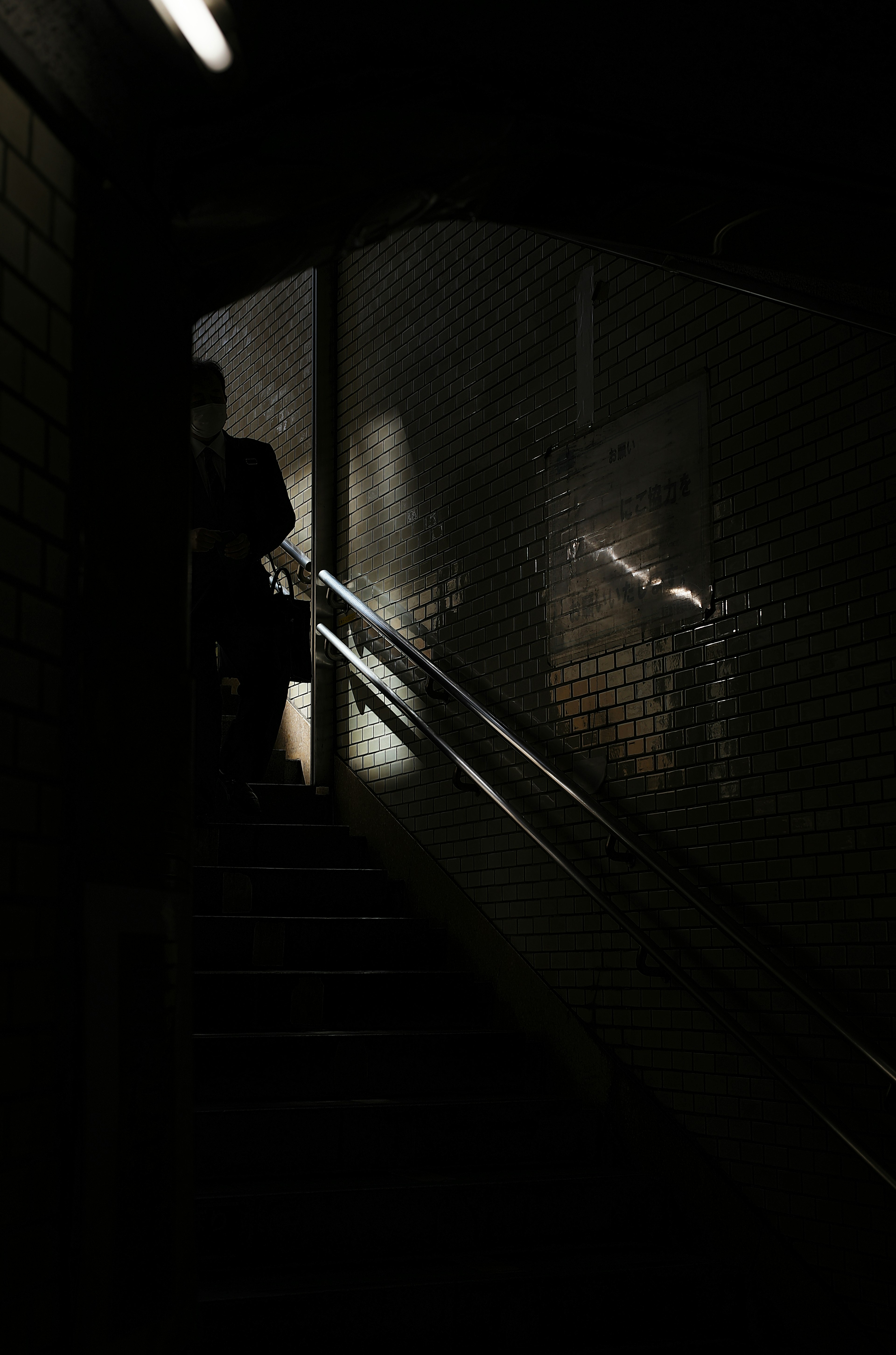 Silhouette d'une personne montant un escalier sombre avec des reflets de lumière