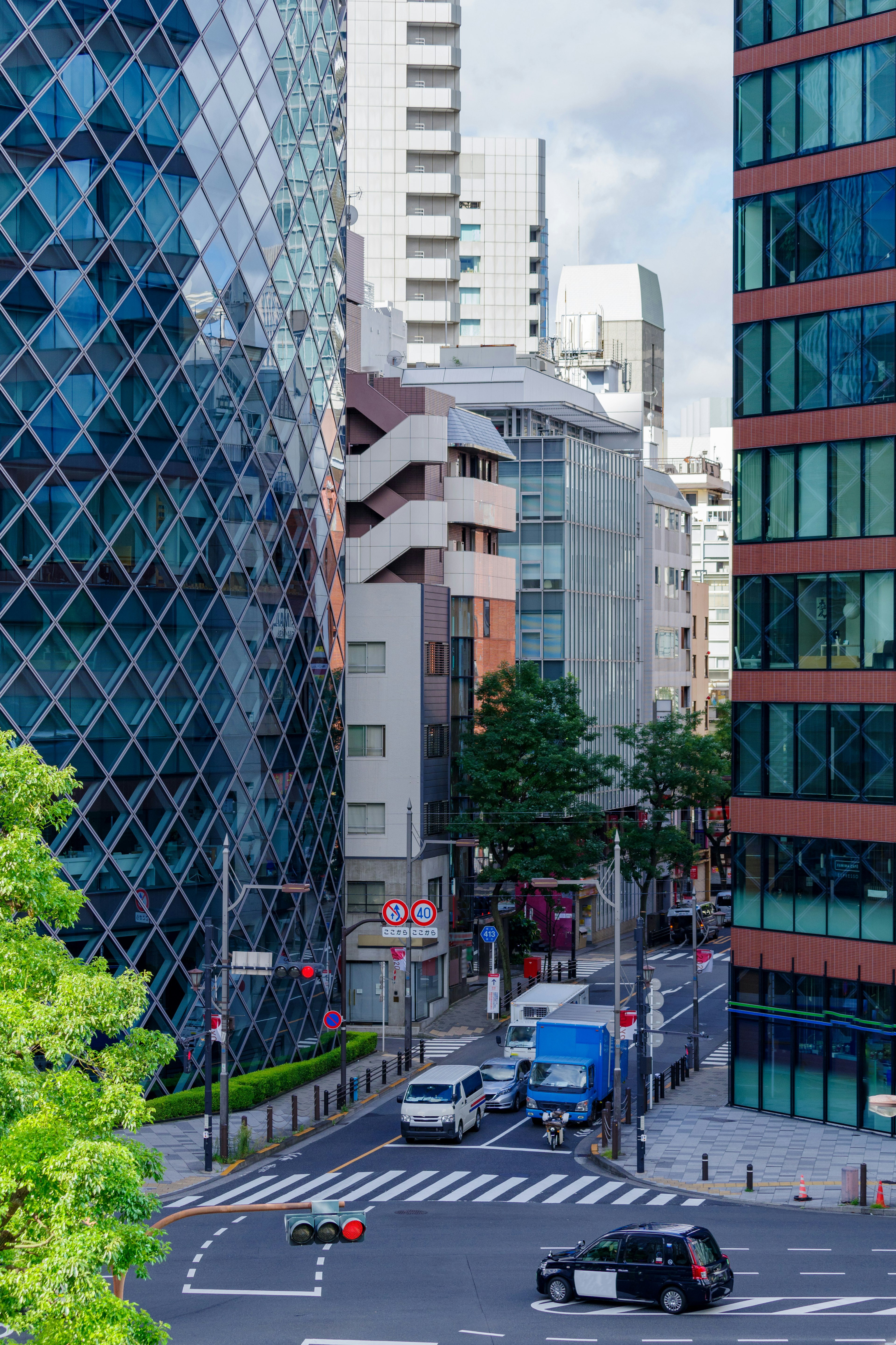 Khung cảnh thành phố Tokyo với các tòa nhà hiện đại và một giao lộ nhộn nhịp có cây xanh xung quanh