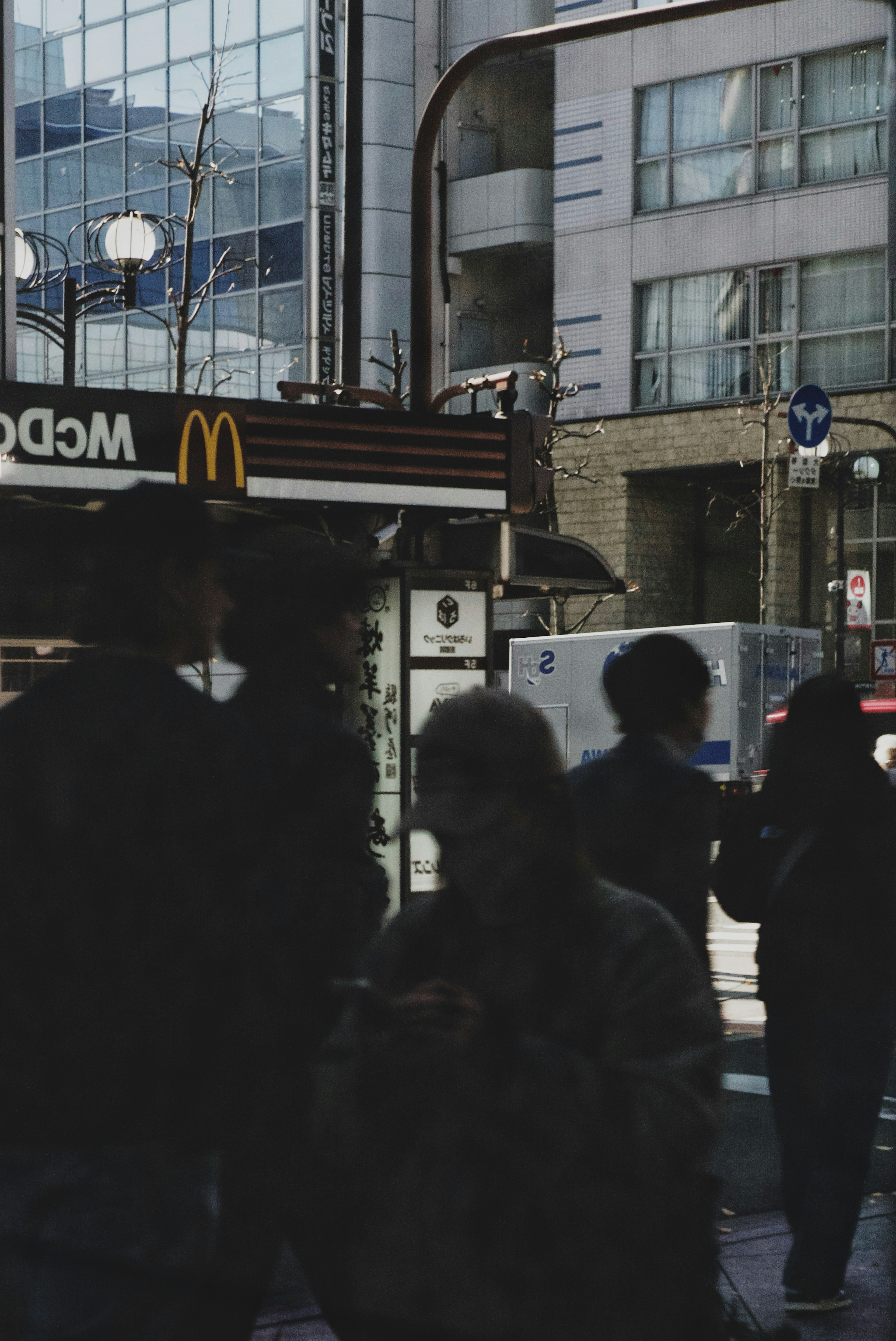 Siluetas de personas en una ciudad con un letrero de McDonald's visible