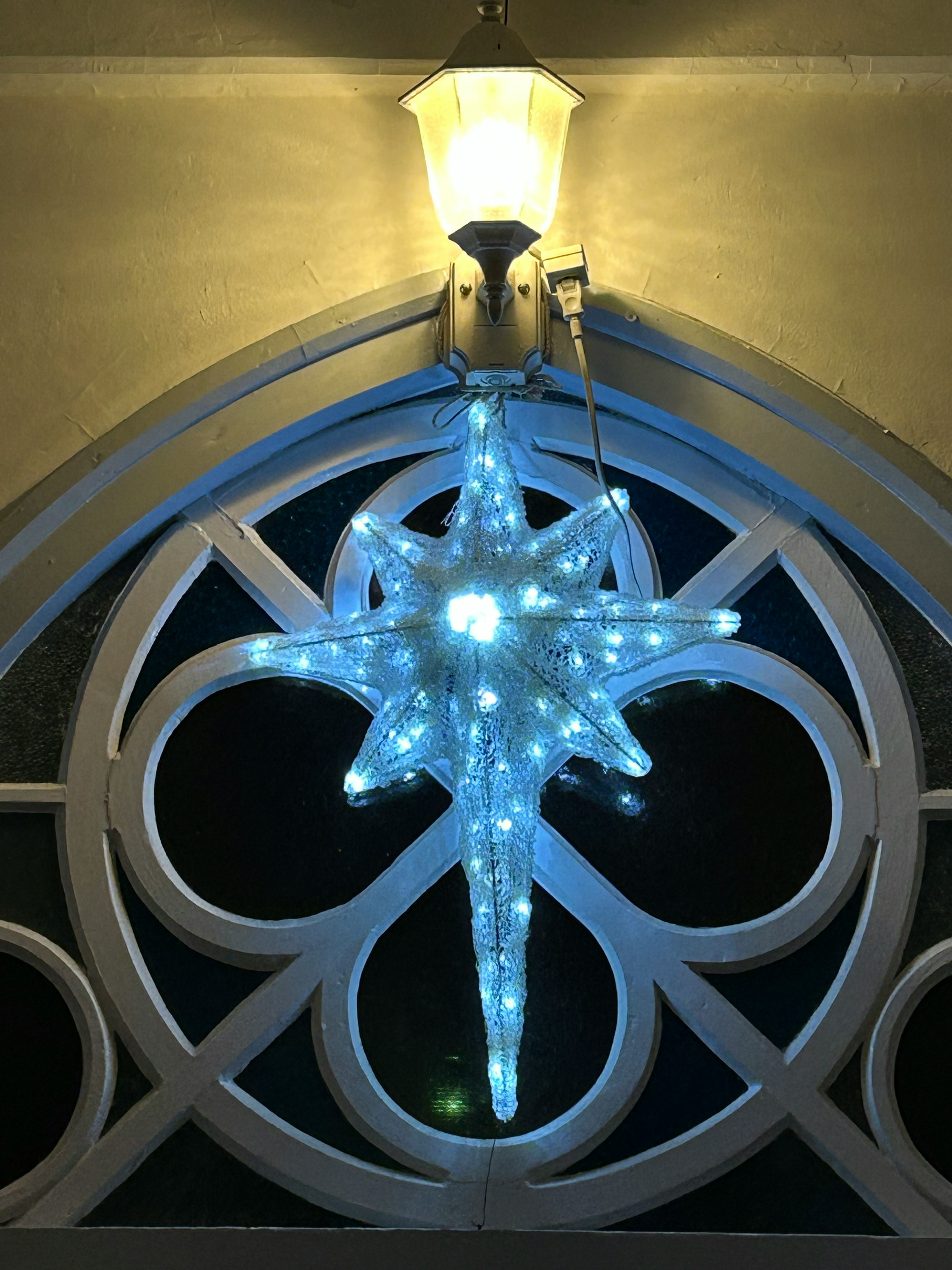 Decoración luminosa en forma de estrella azul colgando en una ventana