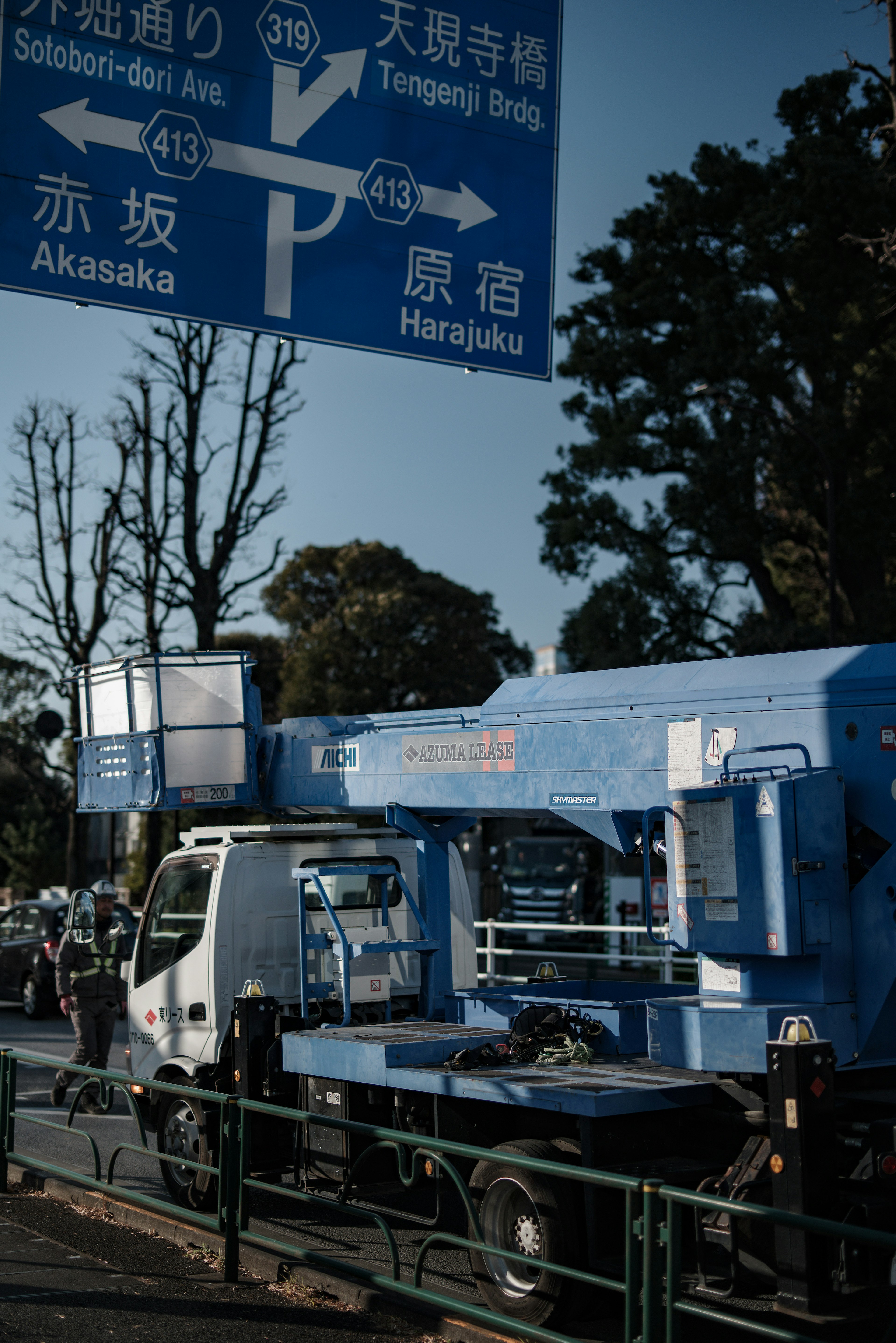 Stadtansicht mit einem blauen Kranwagen und einem Verkehrsschild