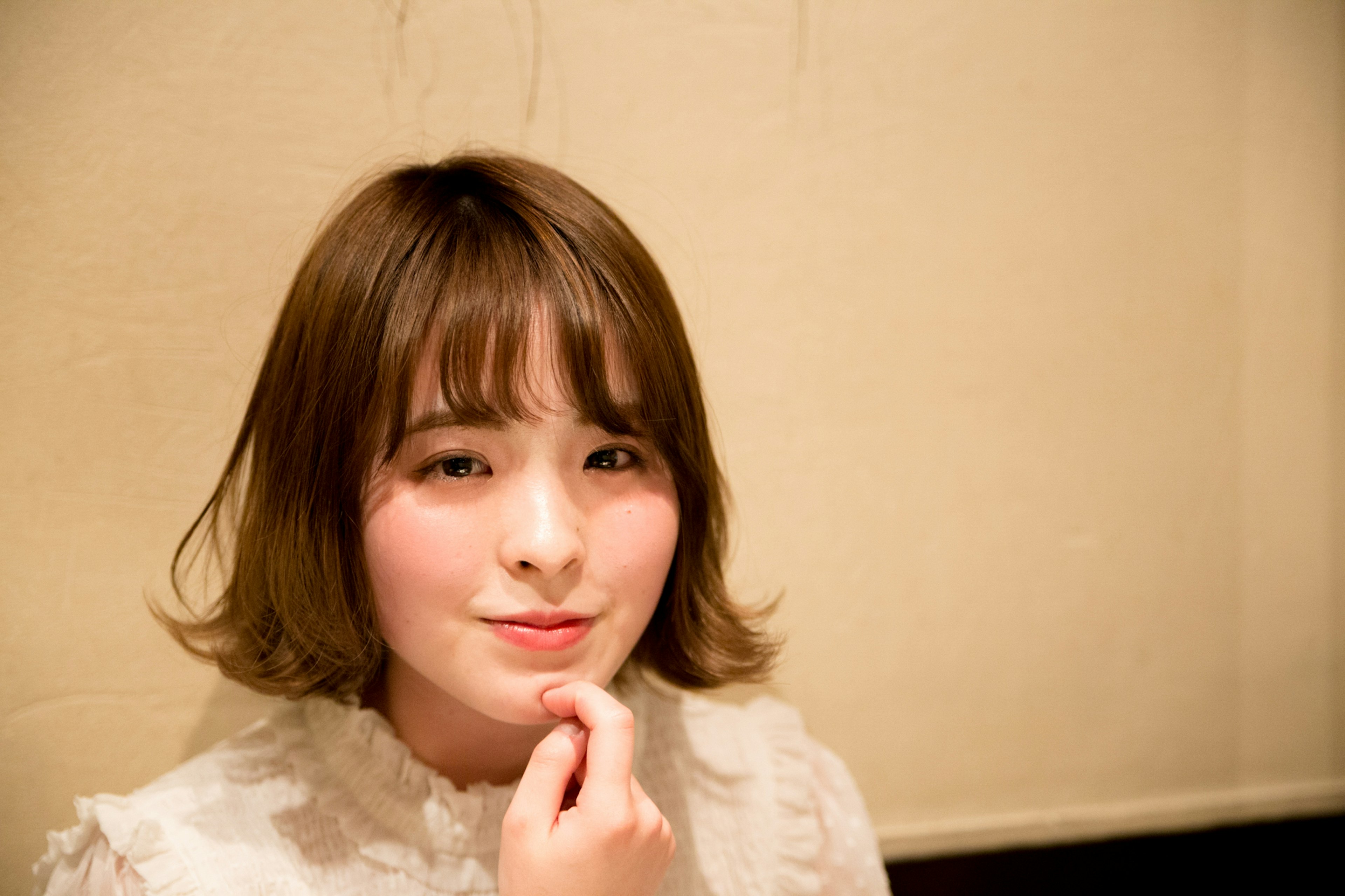 A woman with soft hairstyle smiling in an indoor portrait