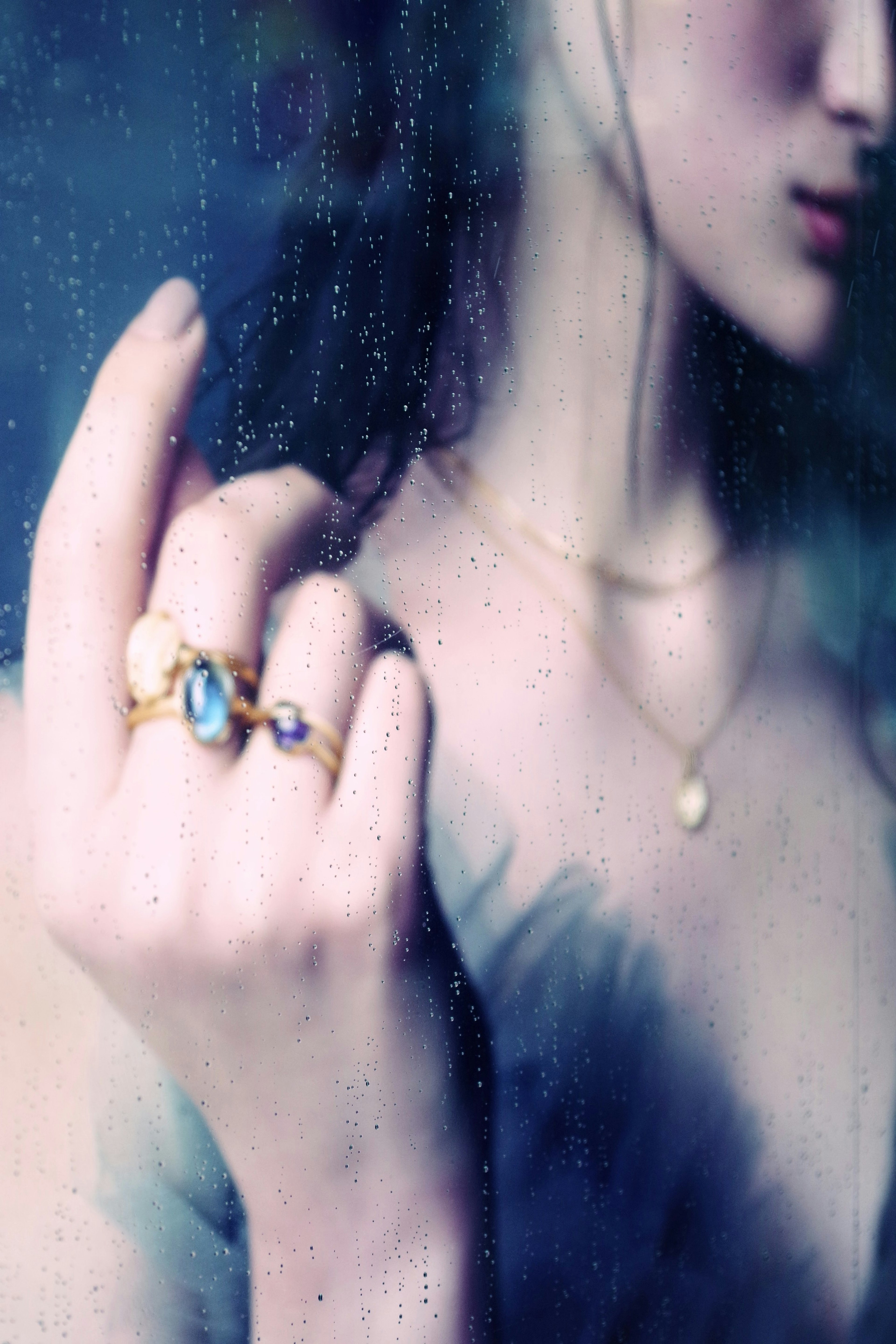 Close-up of a woman's hand adorned with elegant gemstone rings and a delicate necklace