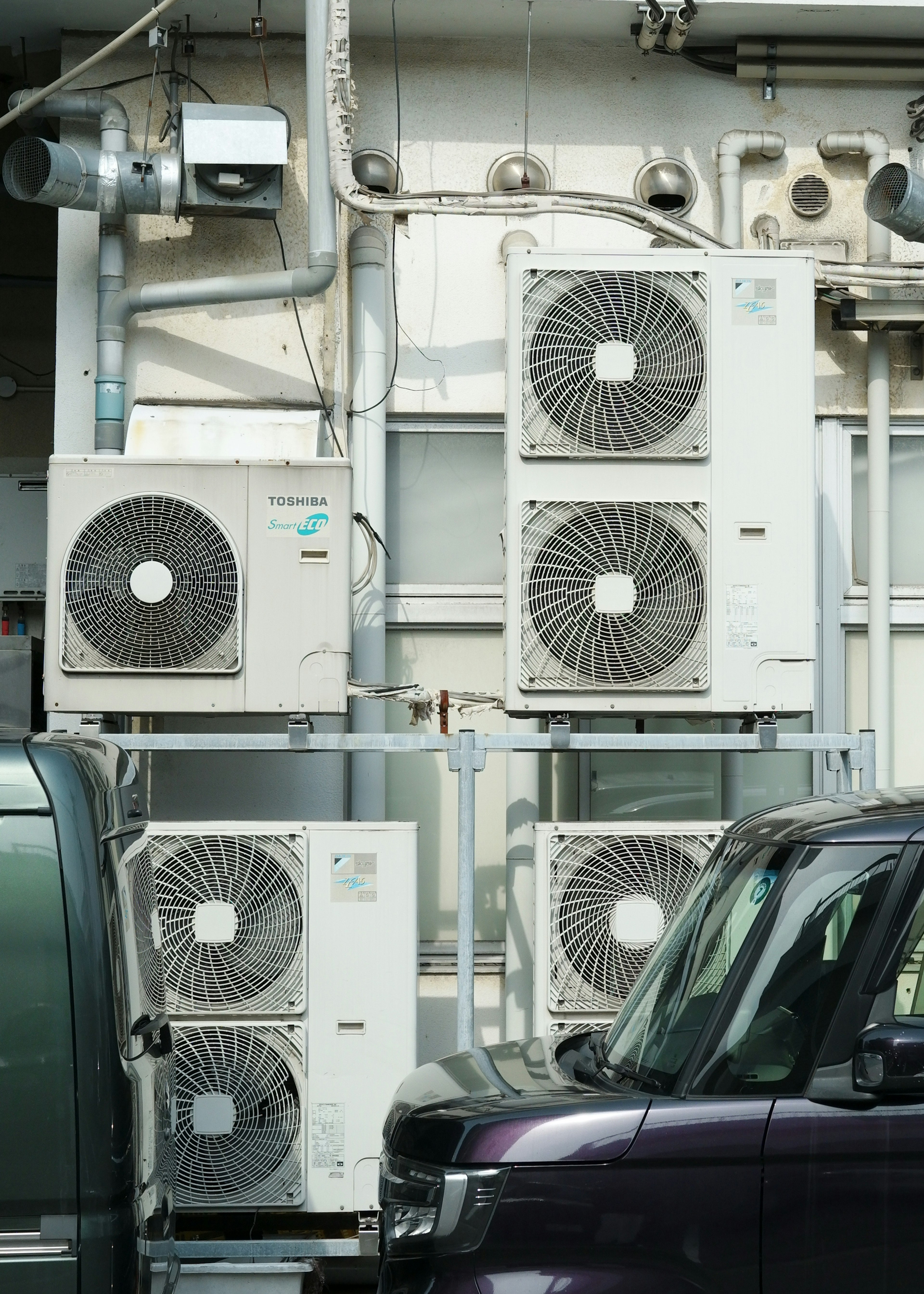 Mehrere Klimaanlagen an einer Wand montiert mit einem Teil eines Fahrzeugs sichtbar