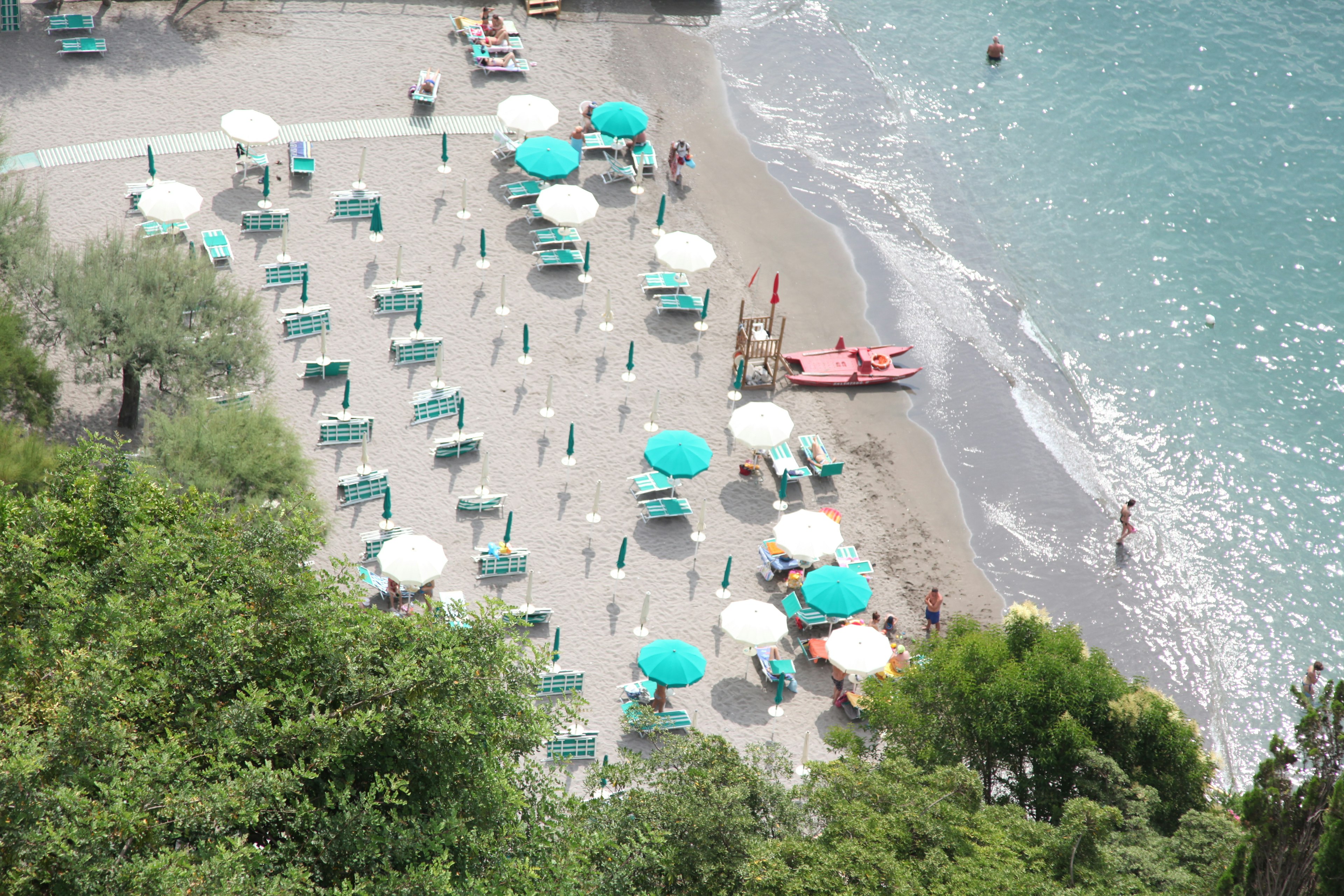 Strandszene mit türkisfarbenen Sonnenschirmen und Liegen