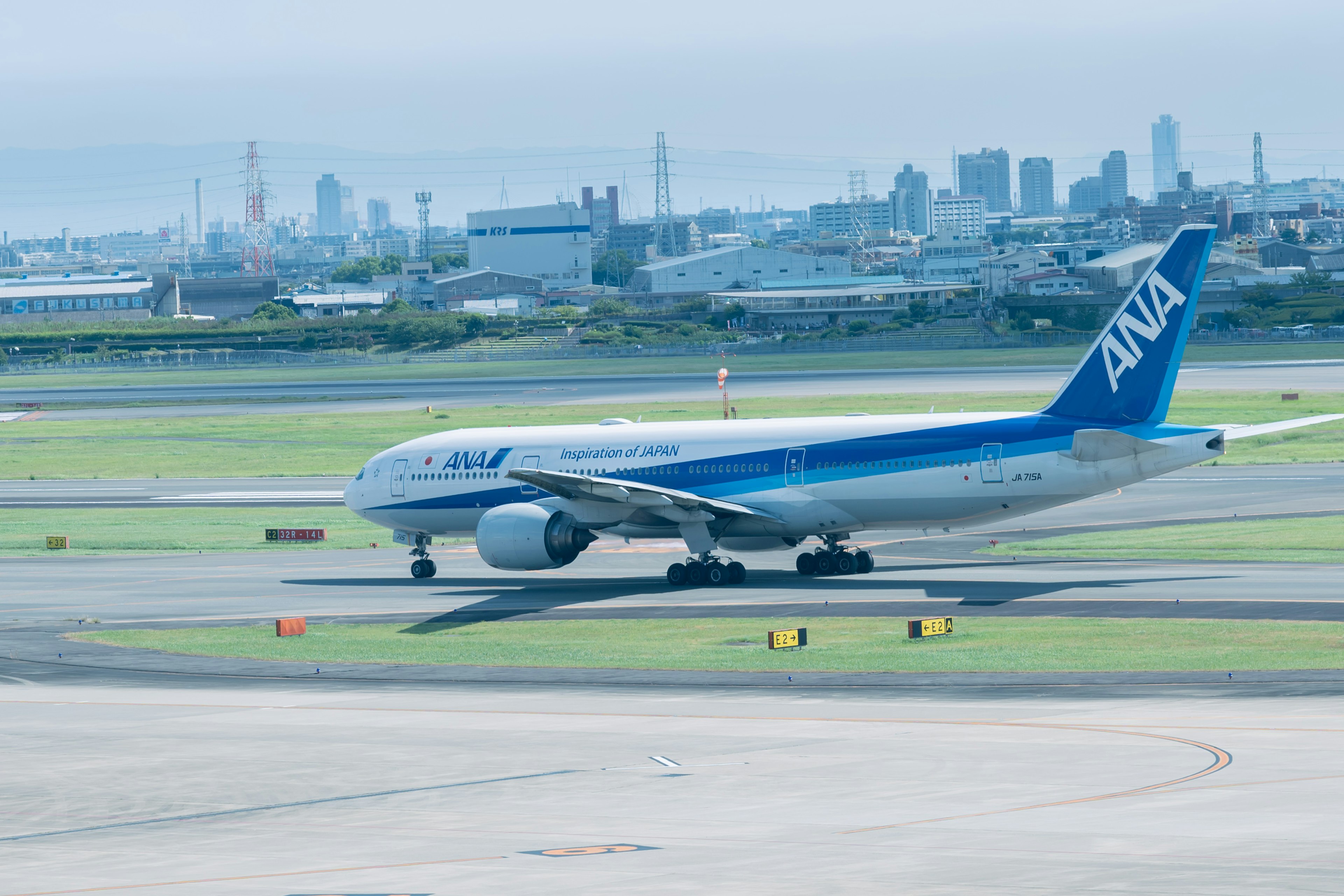 ANA aircraft taxiing on the runway with a city skyline in the background