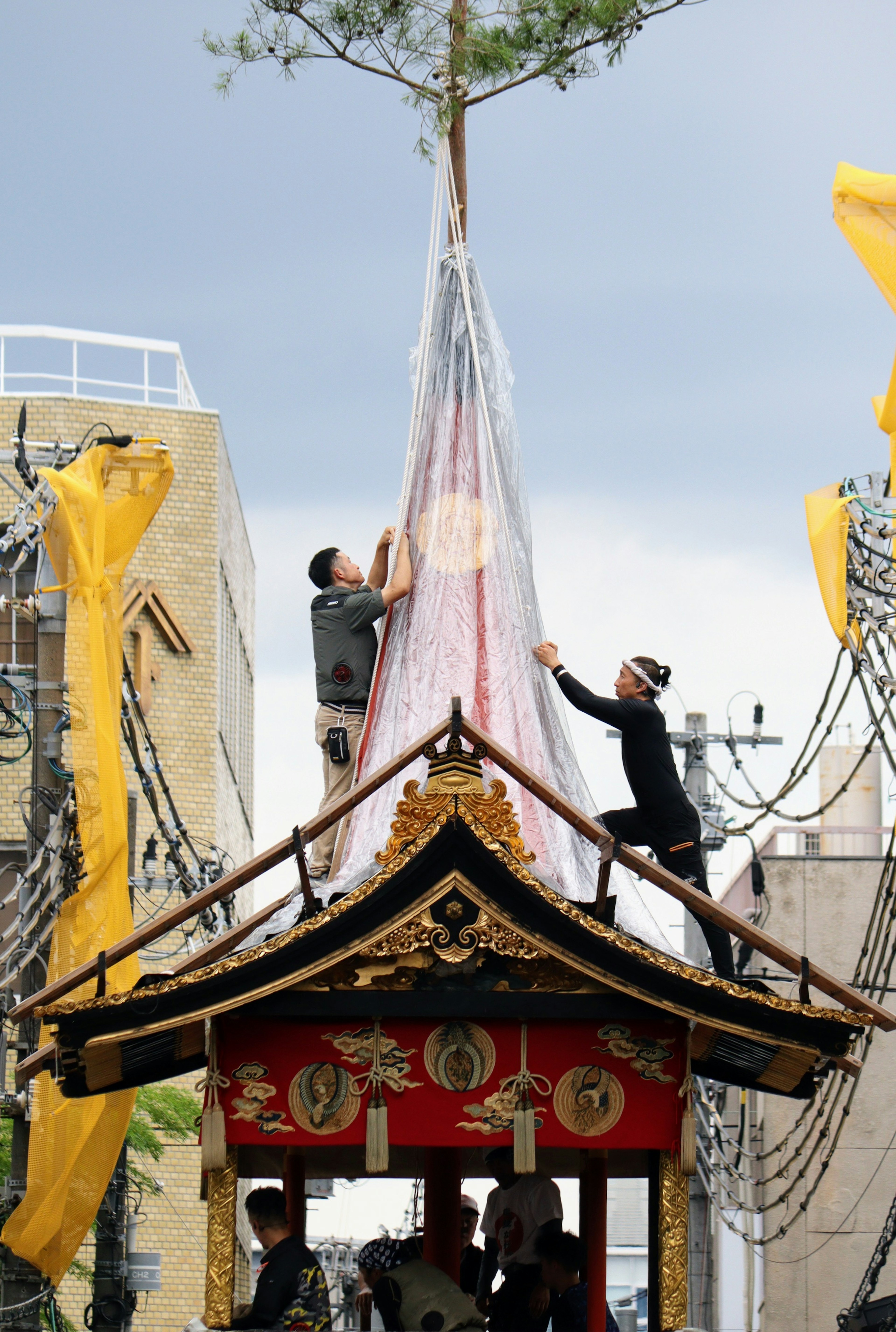 两名工人正在节日花车顶部调整装饰性天篷