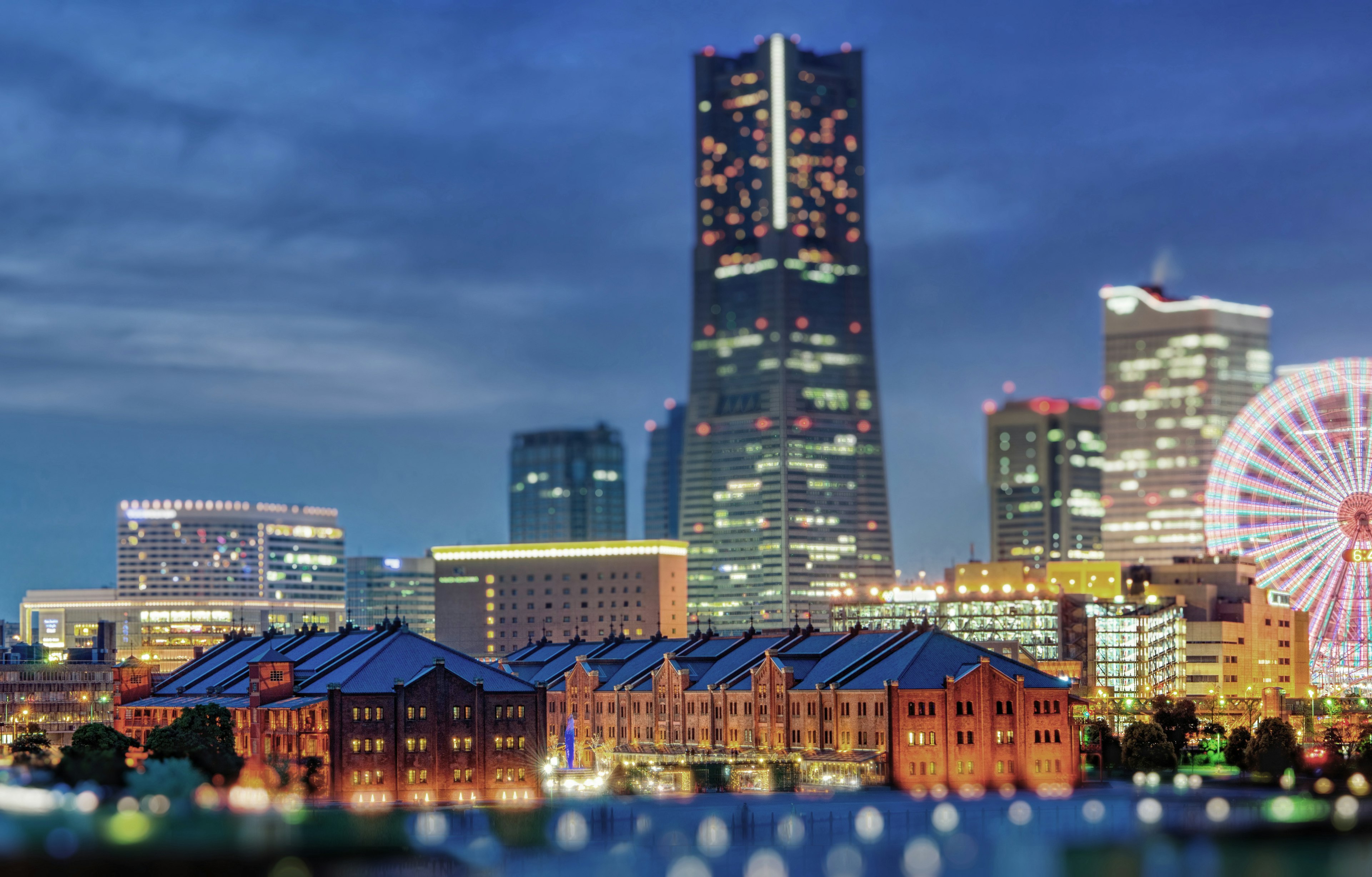 横浜の夜景に照らされたみなとみらい地区の摩天楼と歴史的な赤レンガ倉庫