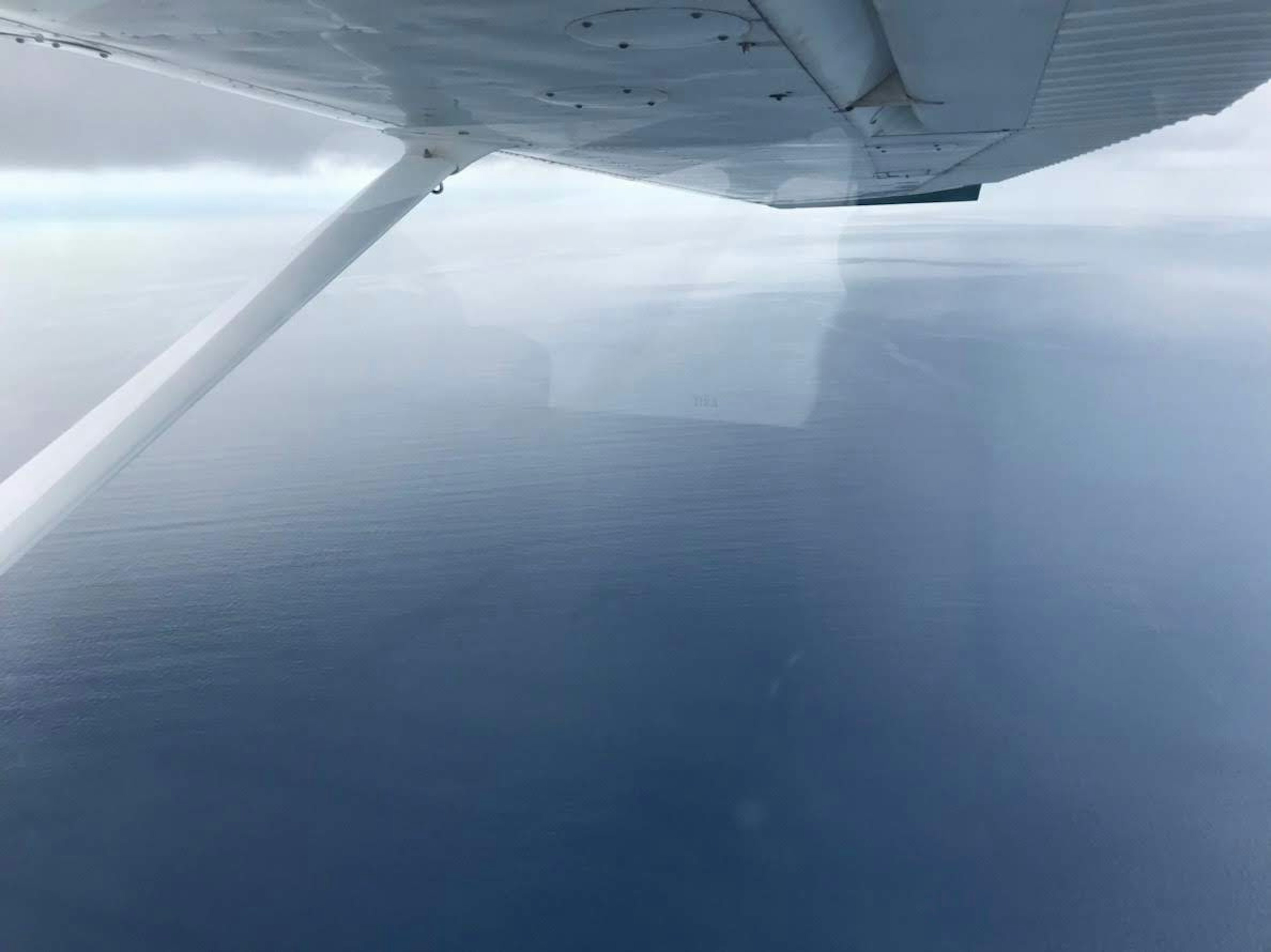 View of the ocean and clouds from an airplane wing