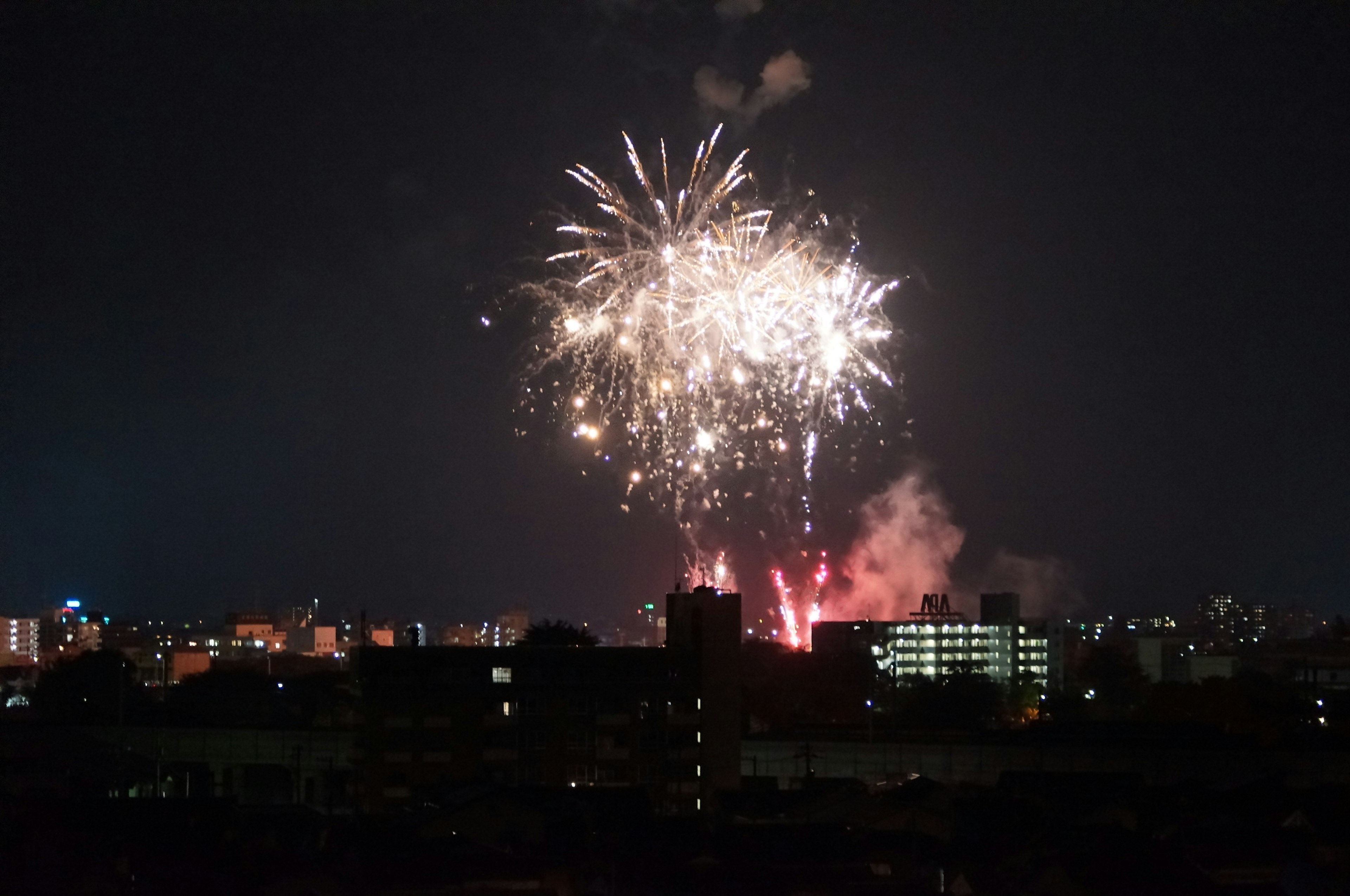 Feuerwerke erhellen den Nachthimmel über einer Stadtlandschaft