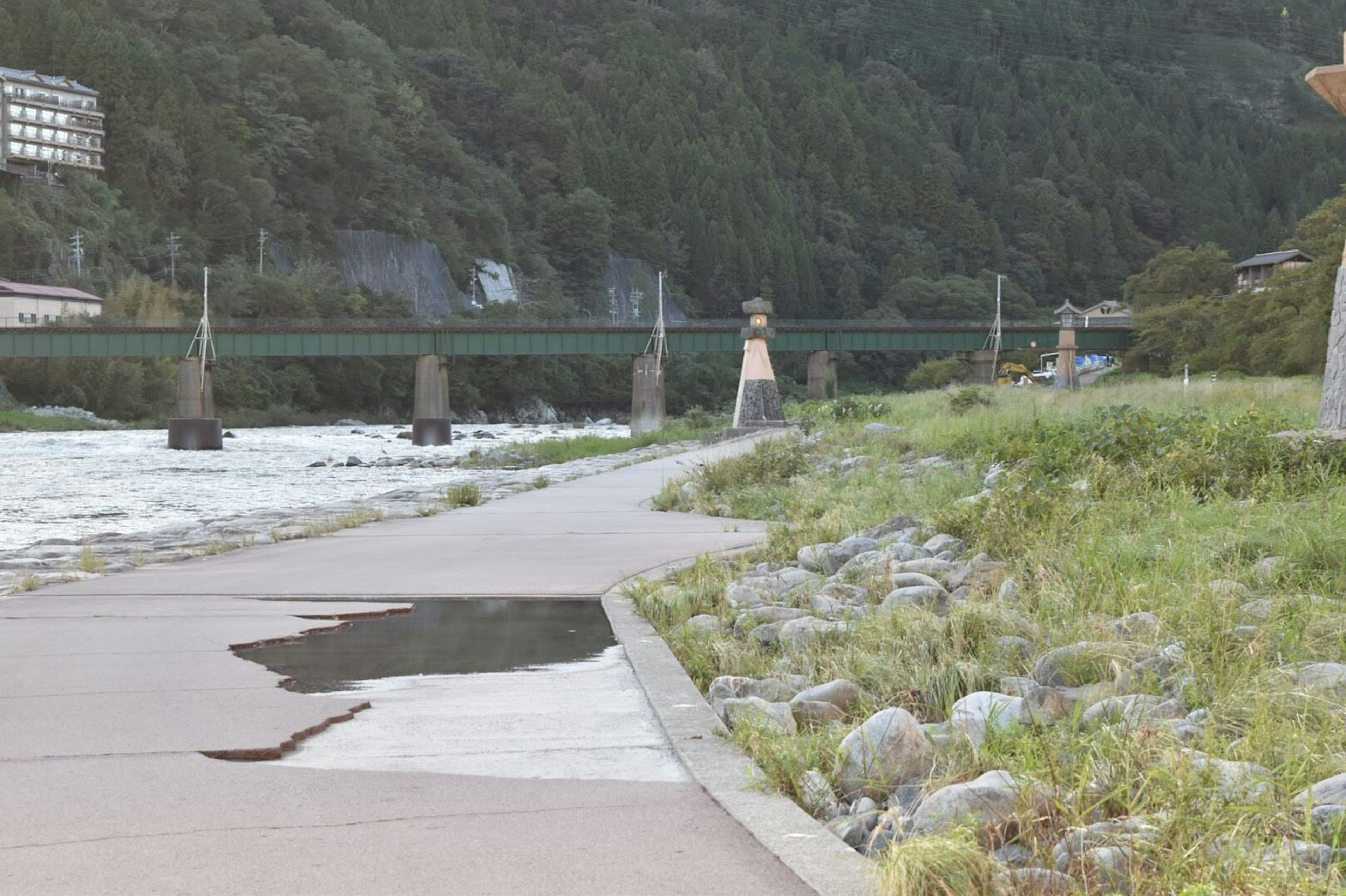 Scenic riverside walkway with a bridge green grass and stones