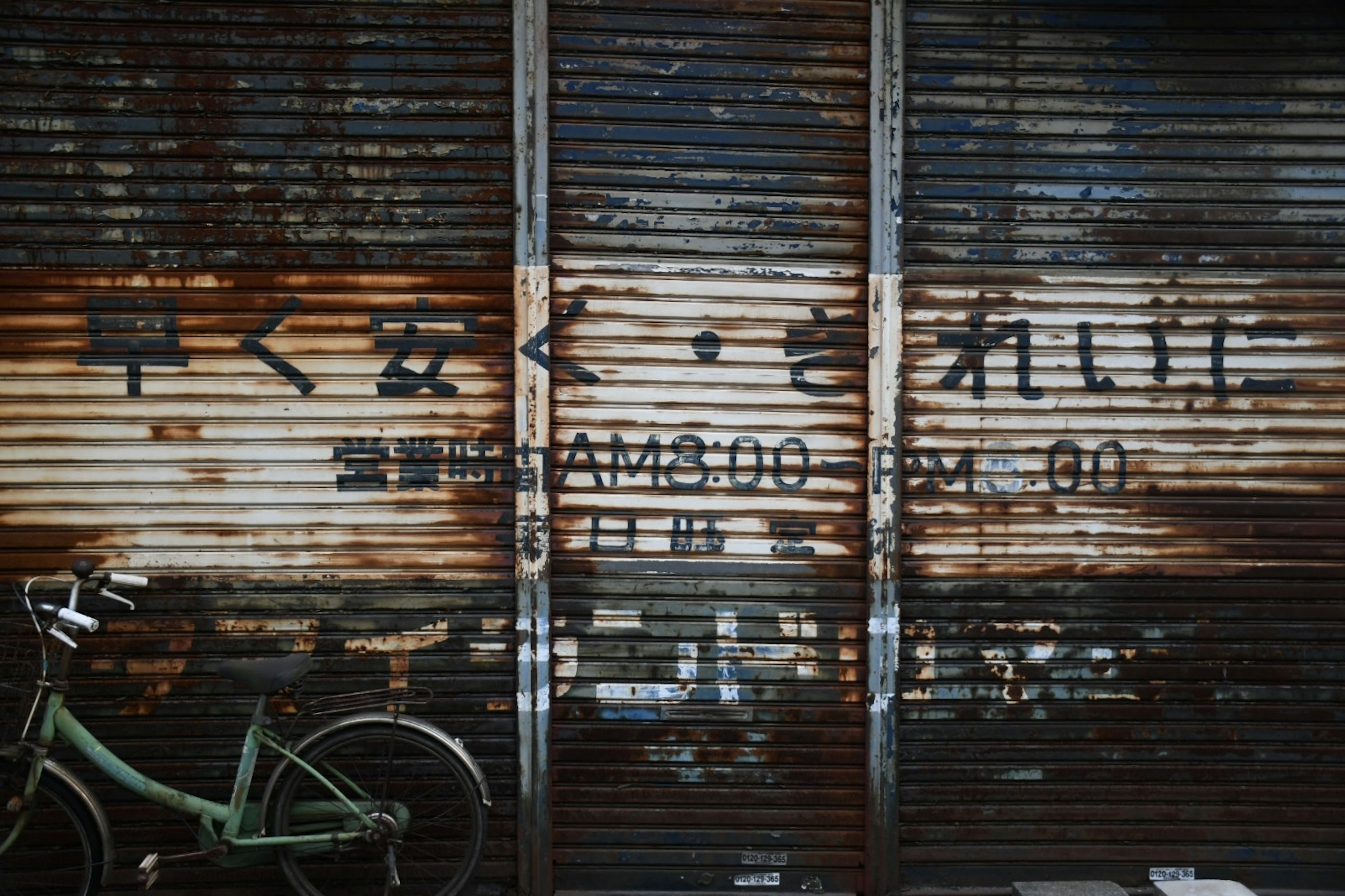 Old shutter with visible text and a bicycle