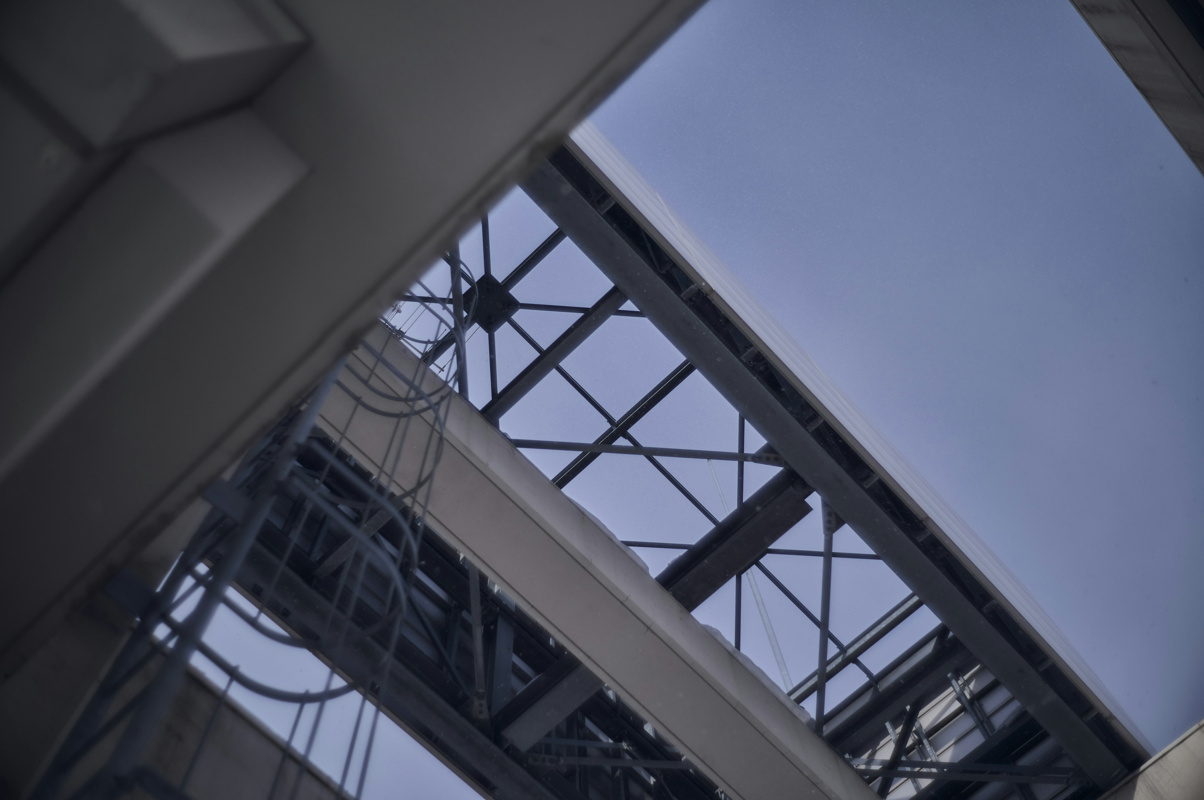 Vista desde debajo de un techo que muestra el cielo azul y la estructura de acero