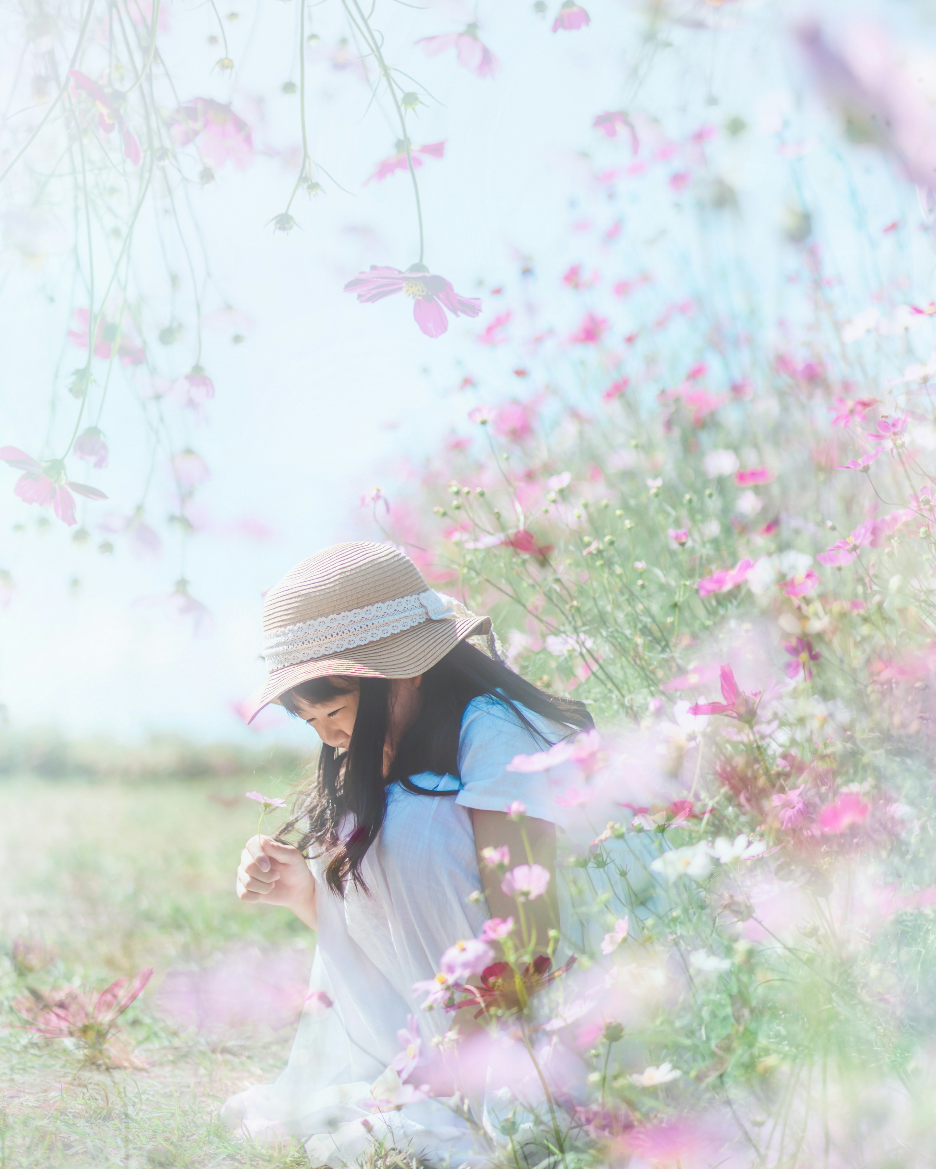 花畑の中で帽子をかぶった女性が微笑んでいる