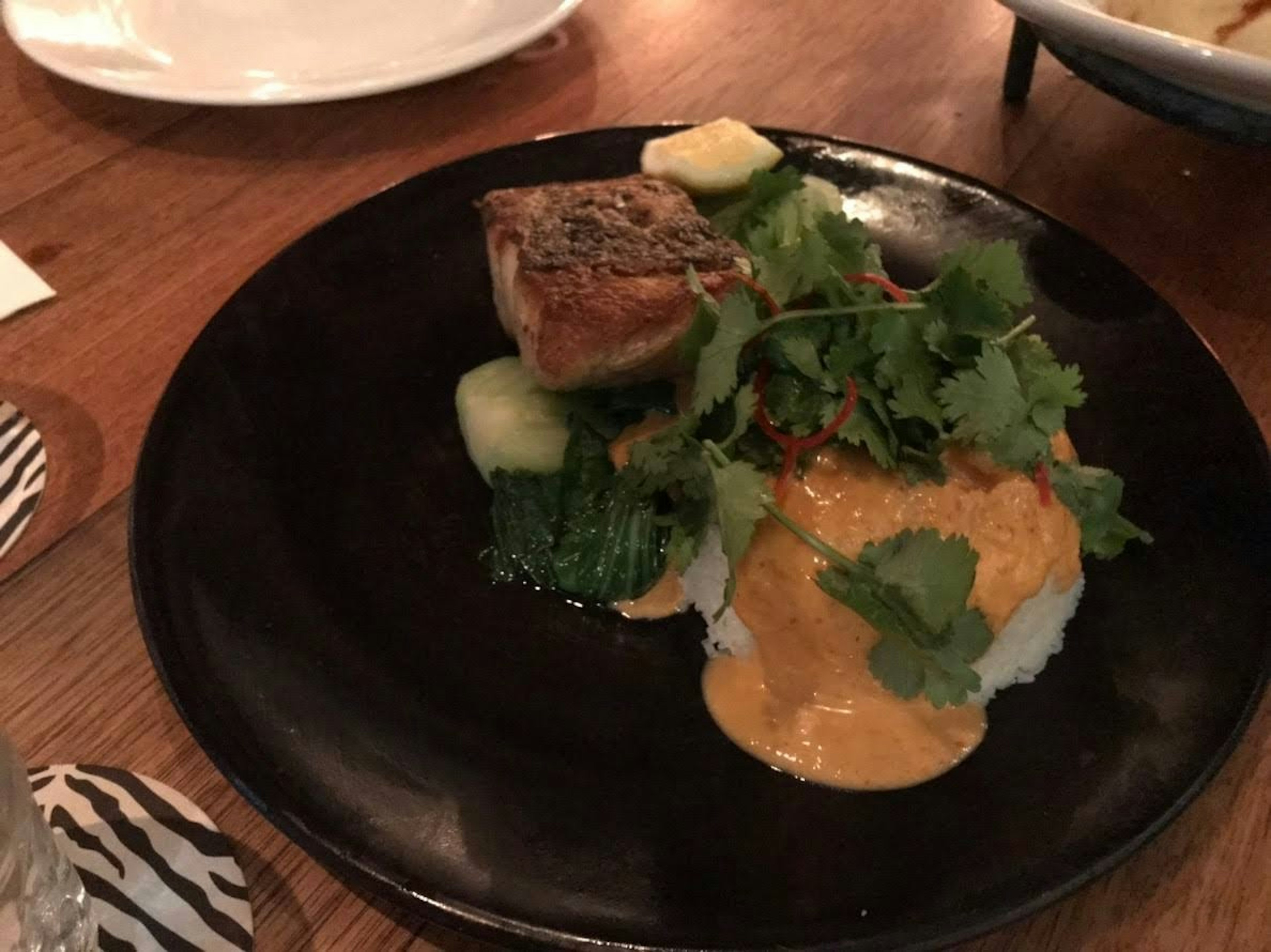 Un plat joliment présenté avec du poisson, du riz et des légumes frais garnis de coriandre