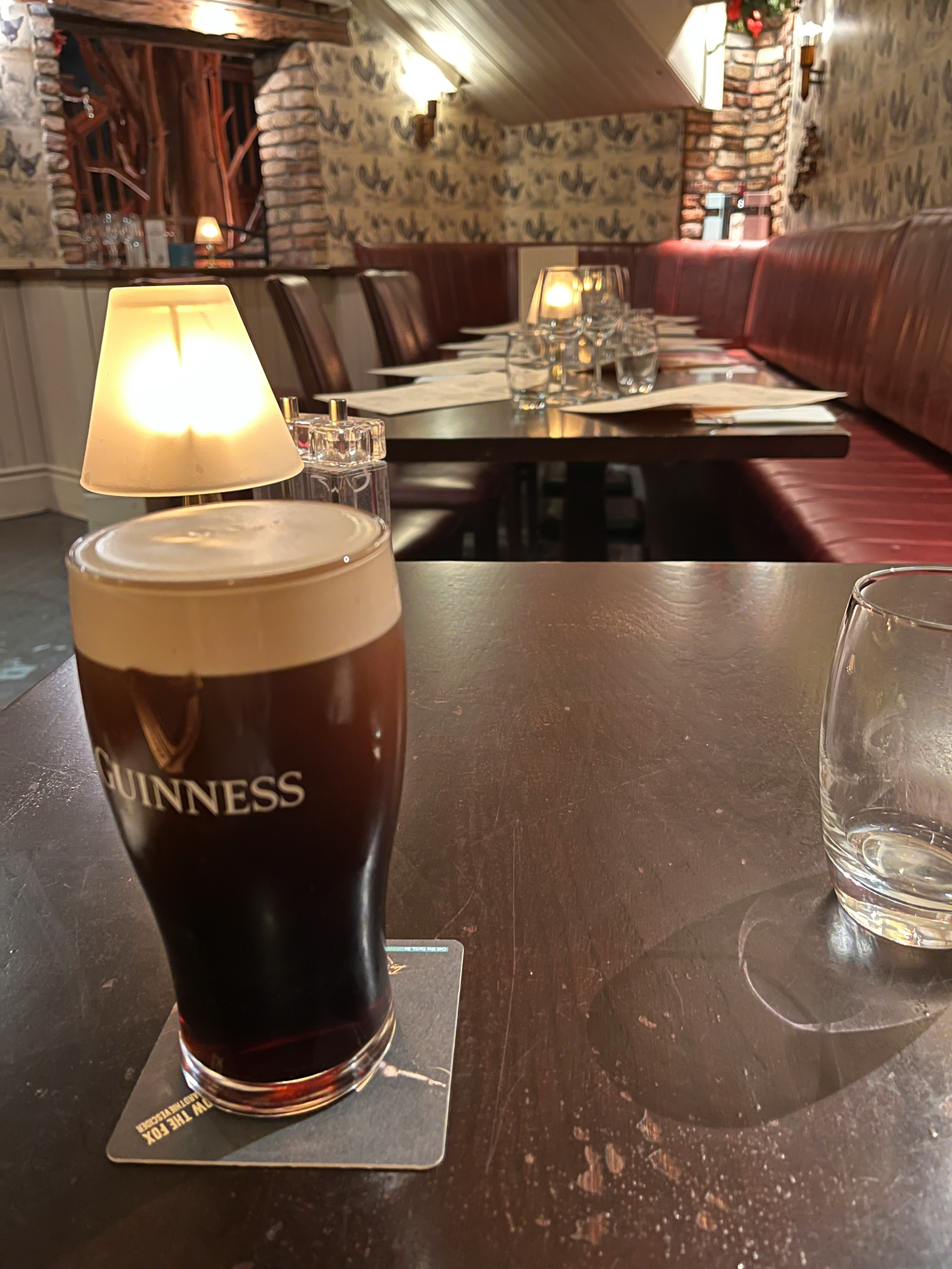 A glass of Guinness beer on a table with a dining area in the background