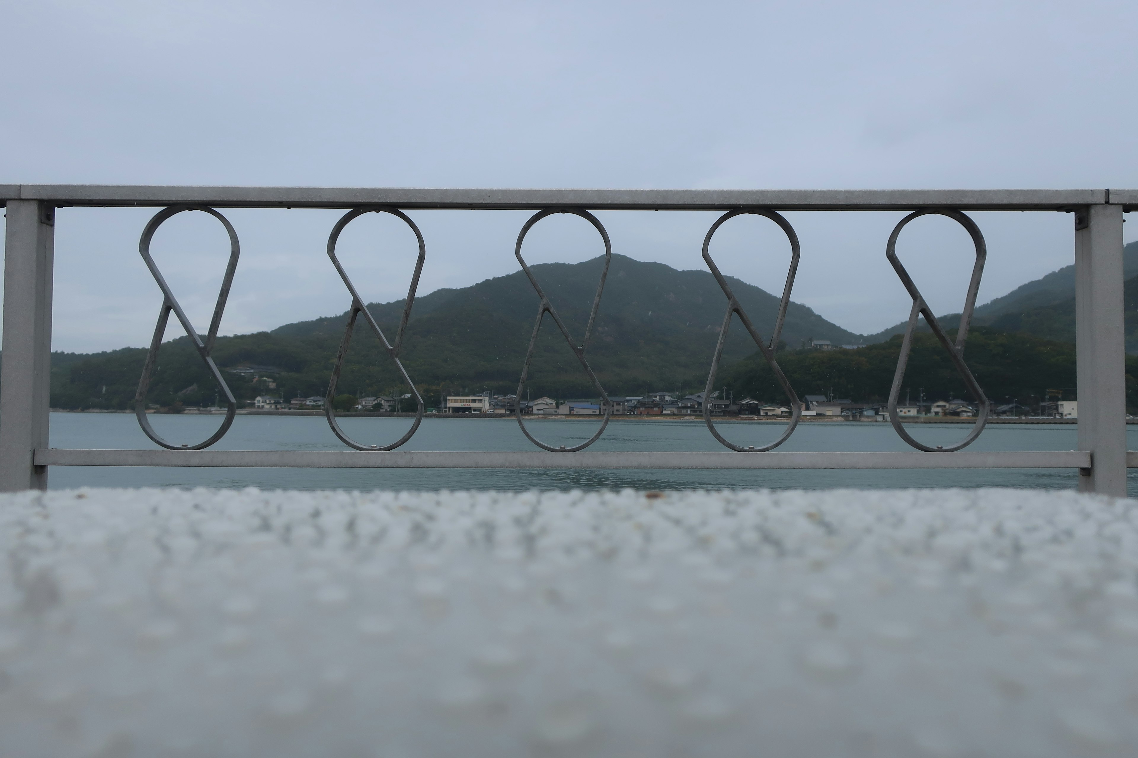 Metal fence with a view of mountains on a cloudy day