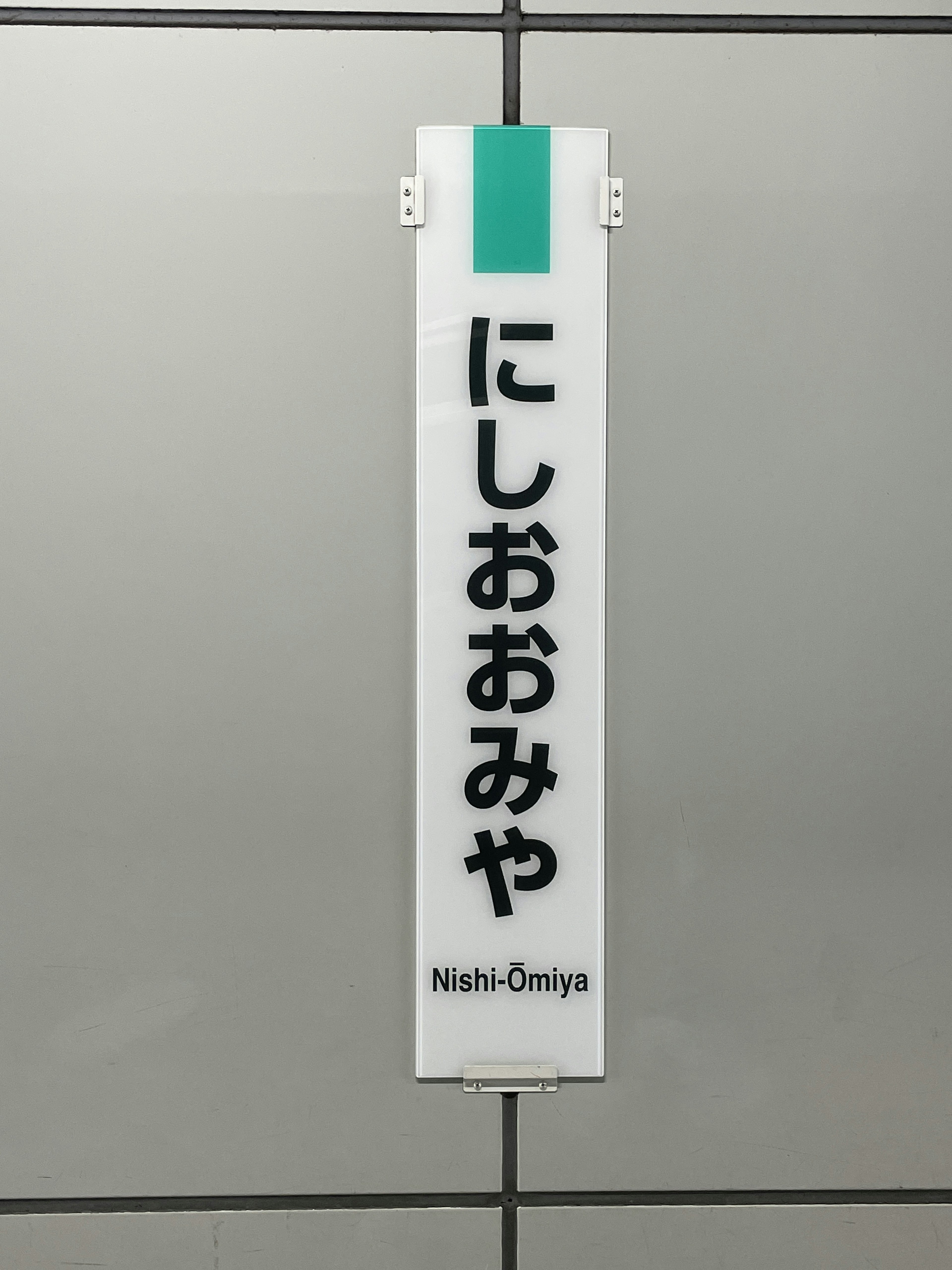 Image of the sign for Nishi-Omiya Station mounted on a wall