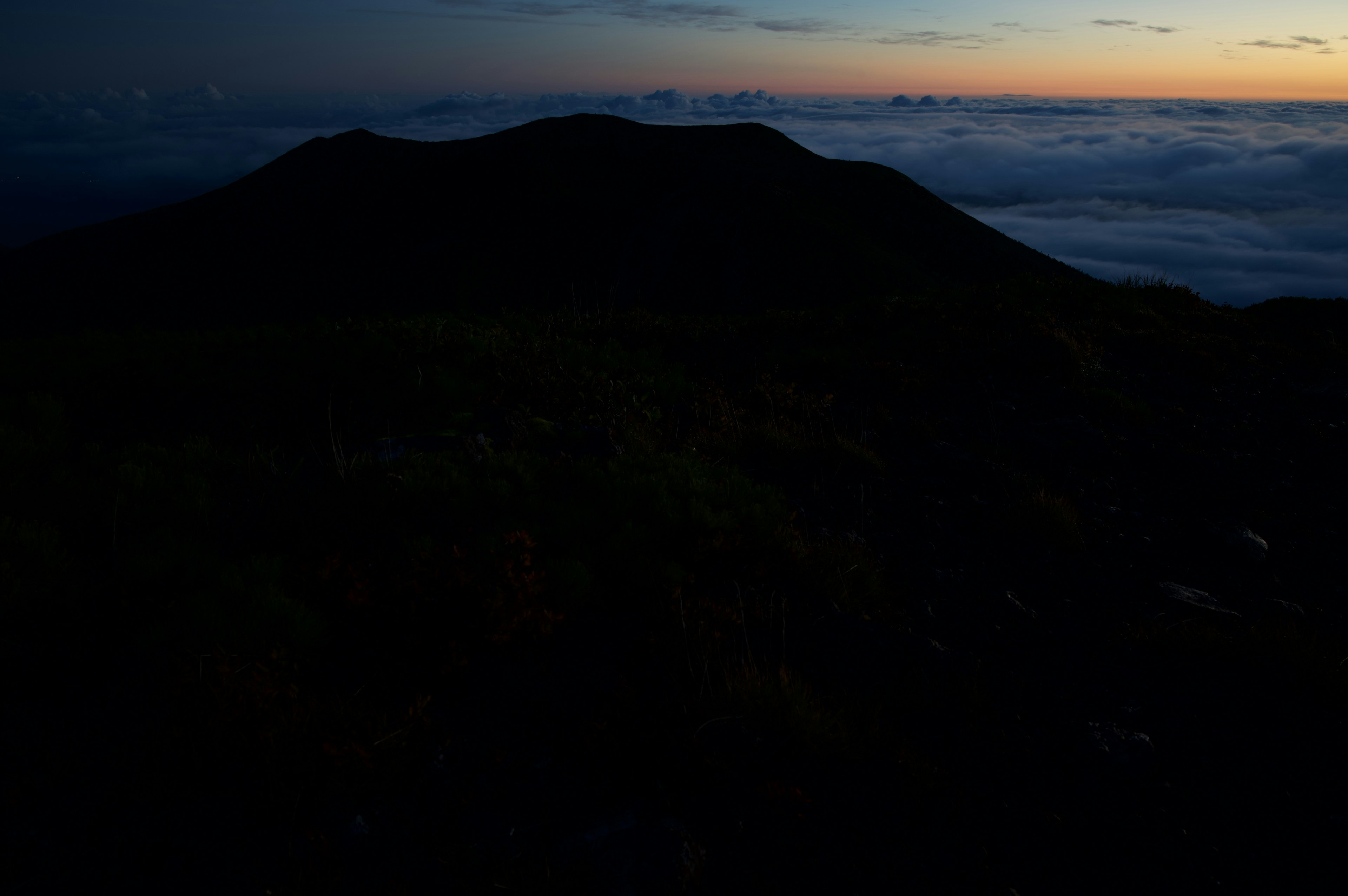 Siluet gelap gunung dengan awan saat matahari terbenam