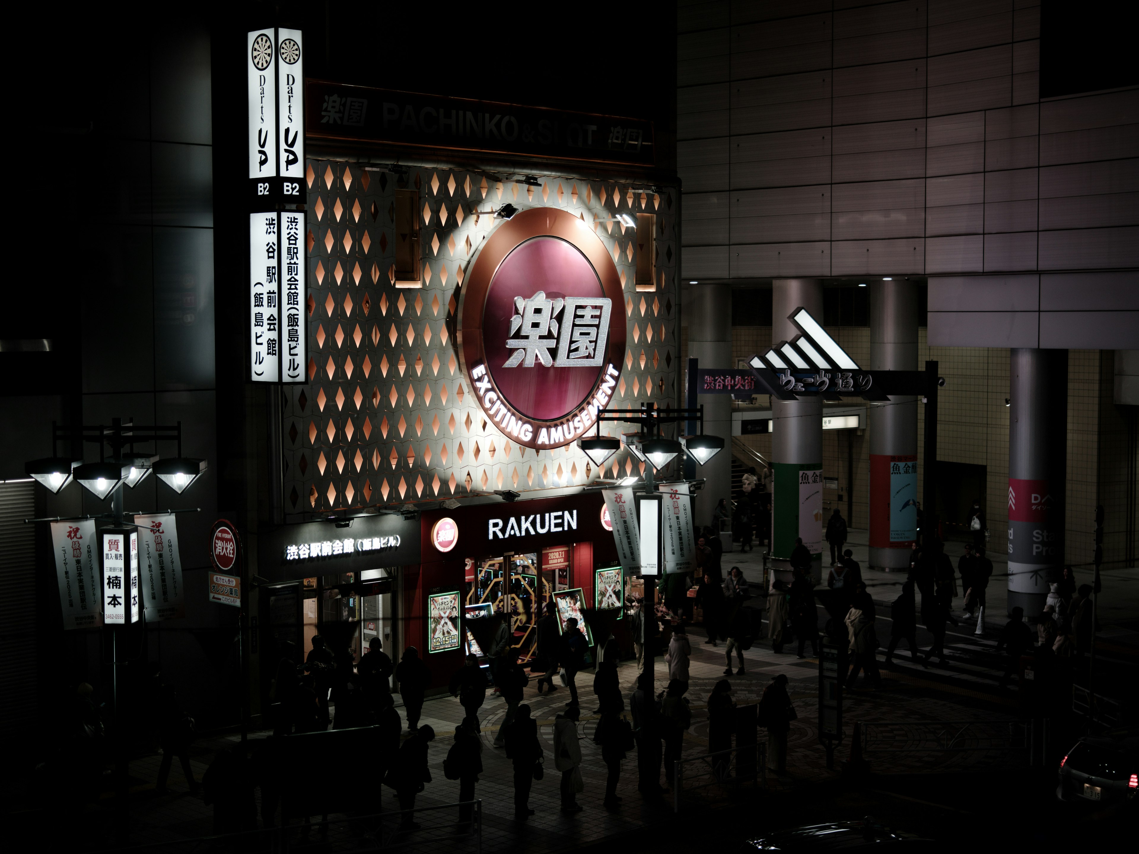 Night scene featuring the Rakuen sign and a line of people