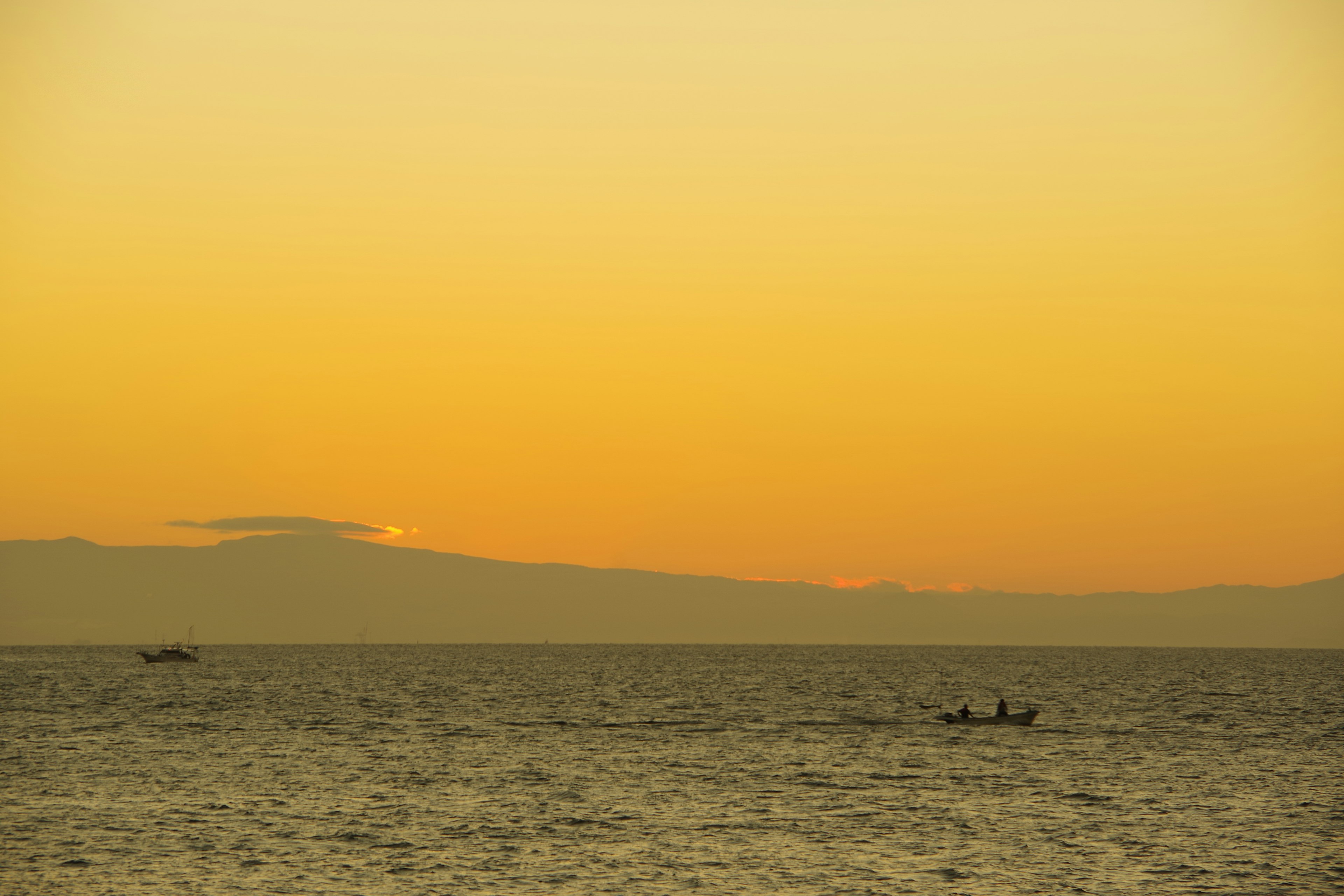 Silhouette di piccole barche da pesca su un oceano al tramonto