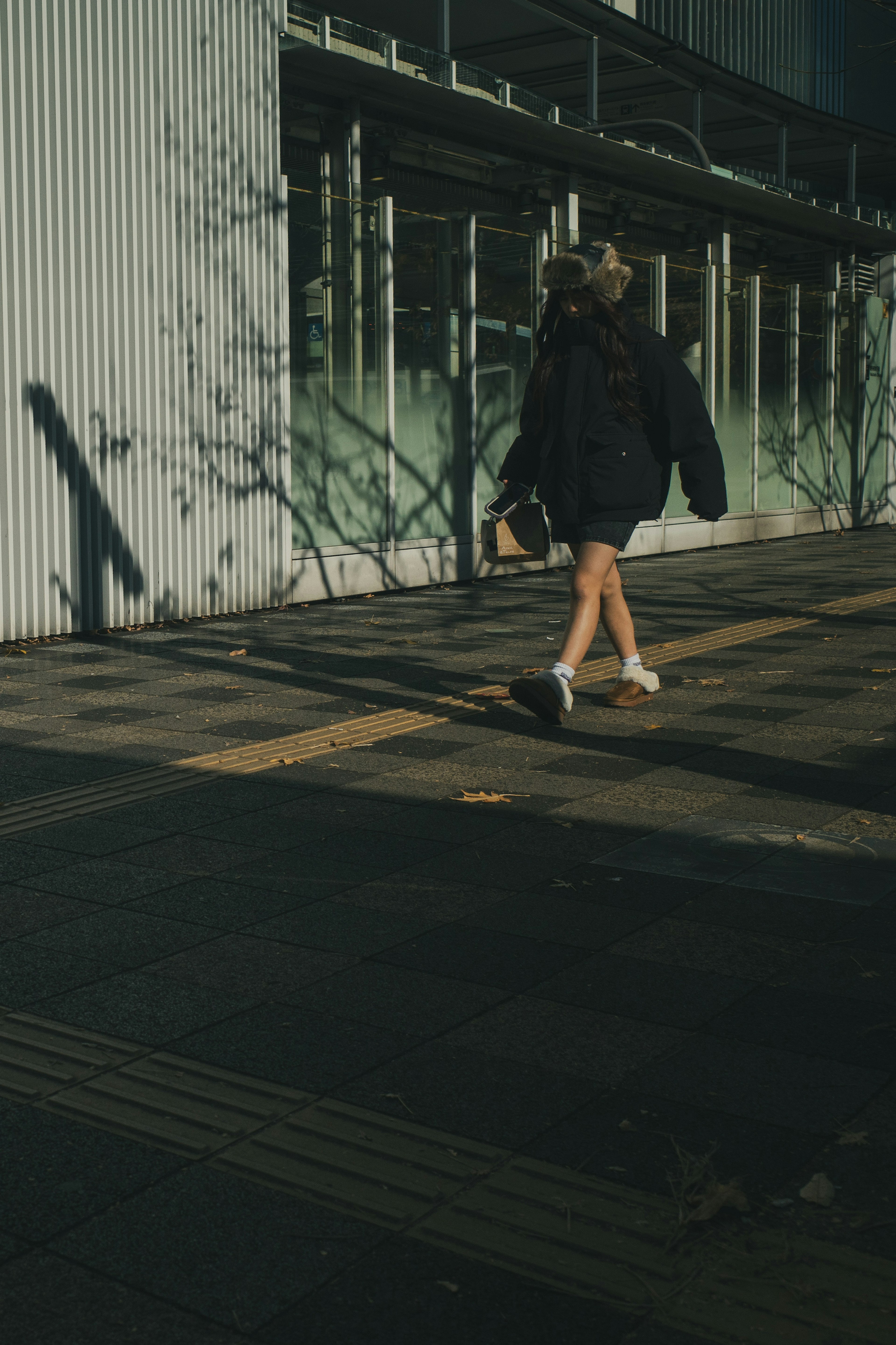 Eine Frau in schwarzer Jacke, die auf einer Stadtstraße geht