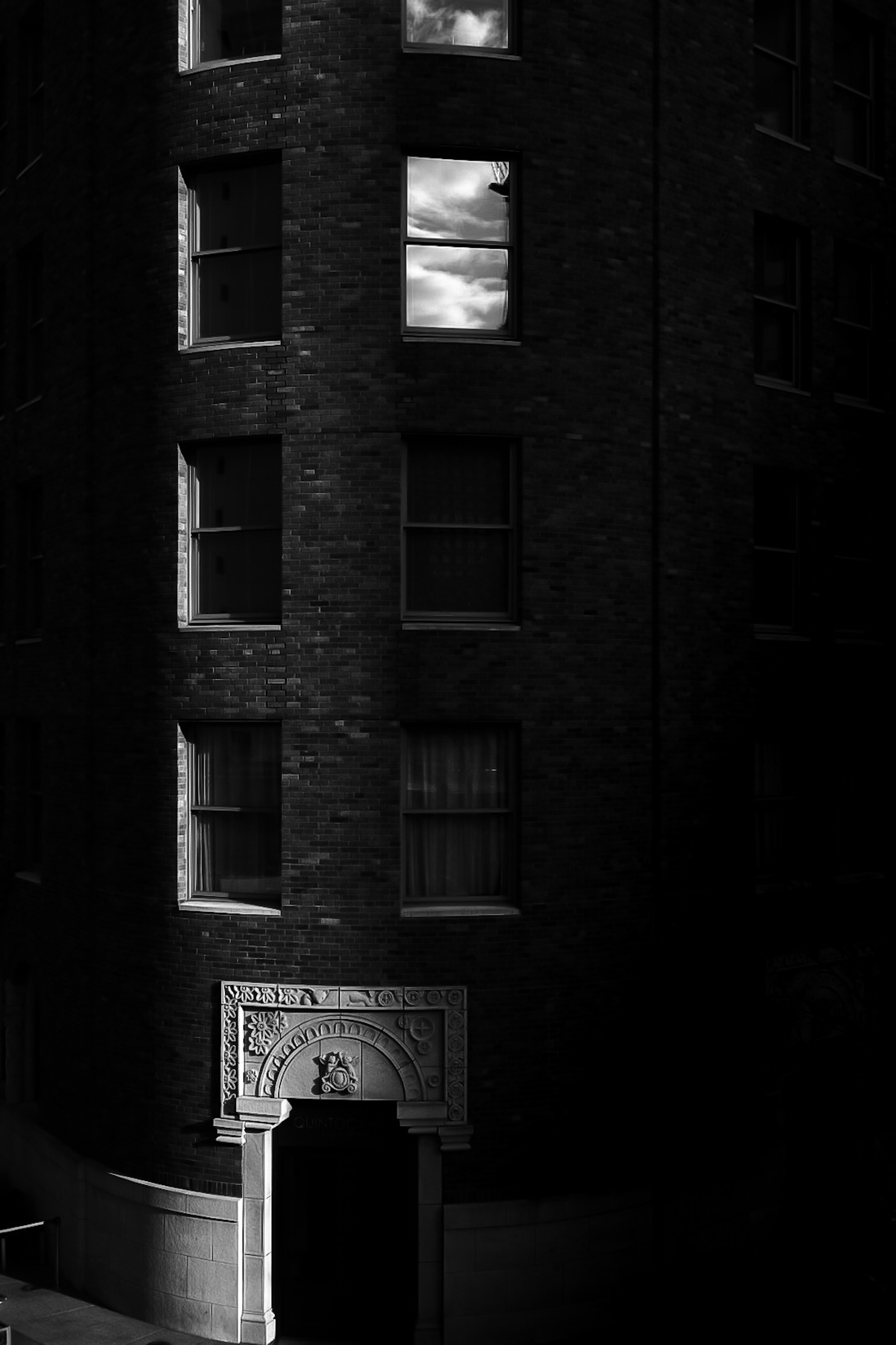 Exterior of a building in black and white tones Reflection of clouds visible in the windows Art Deco style entrance
