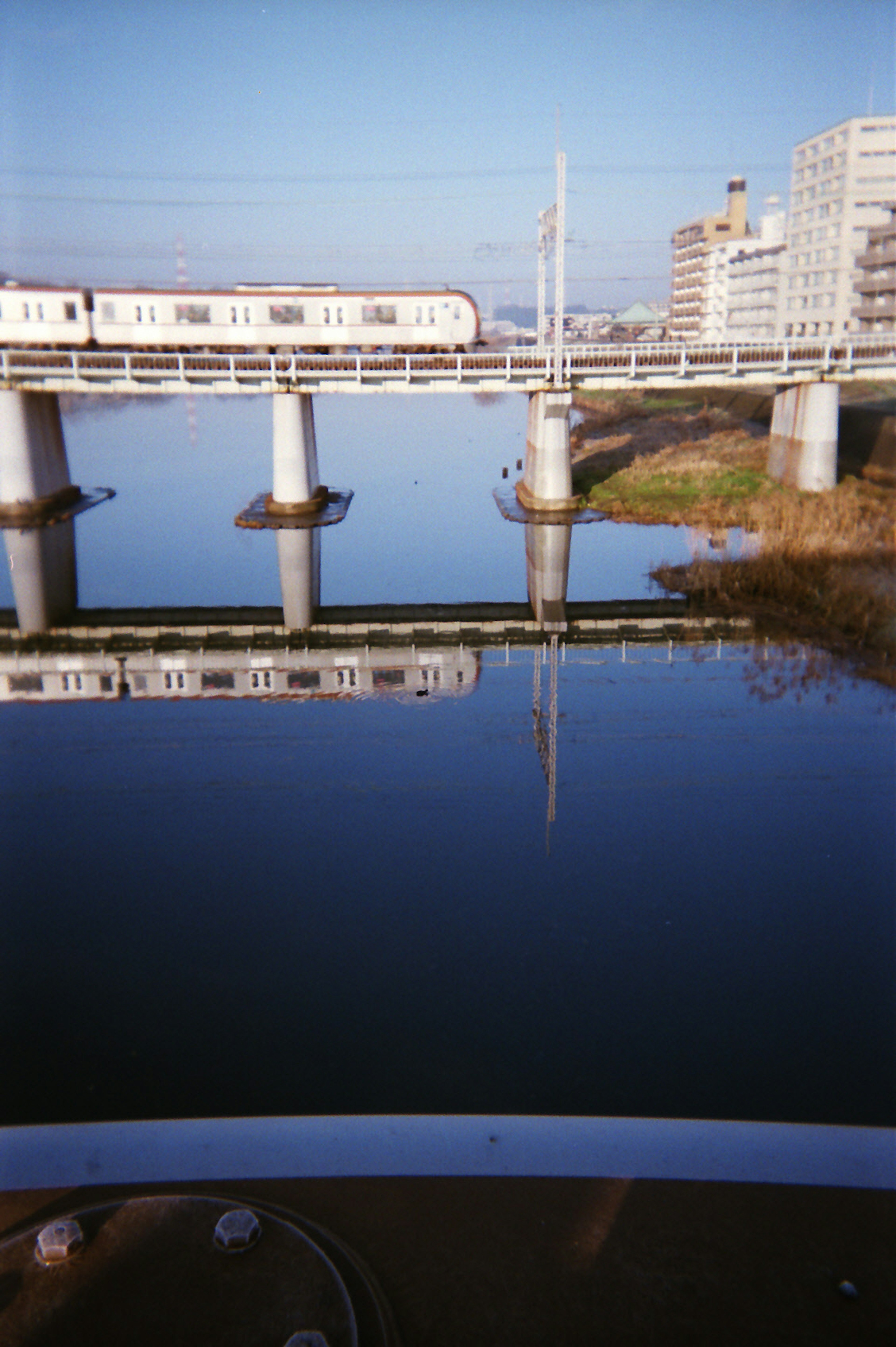 Refleksi jembatan kereta api dan kereta di atas sungai