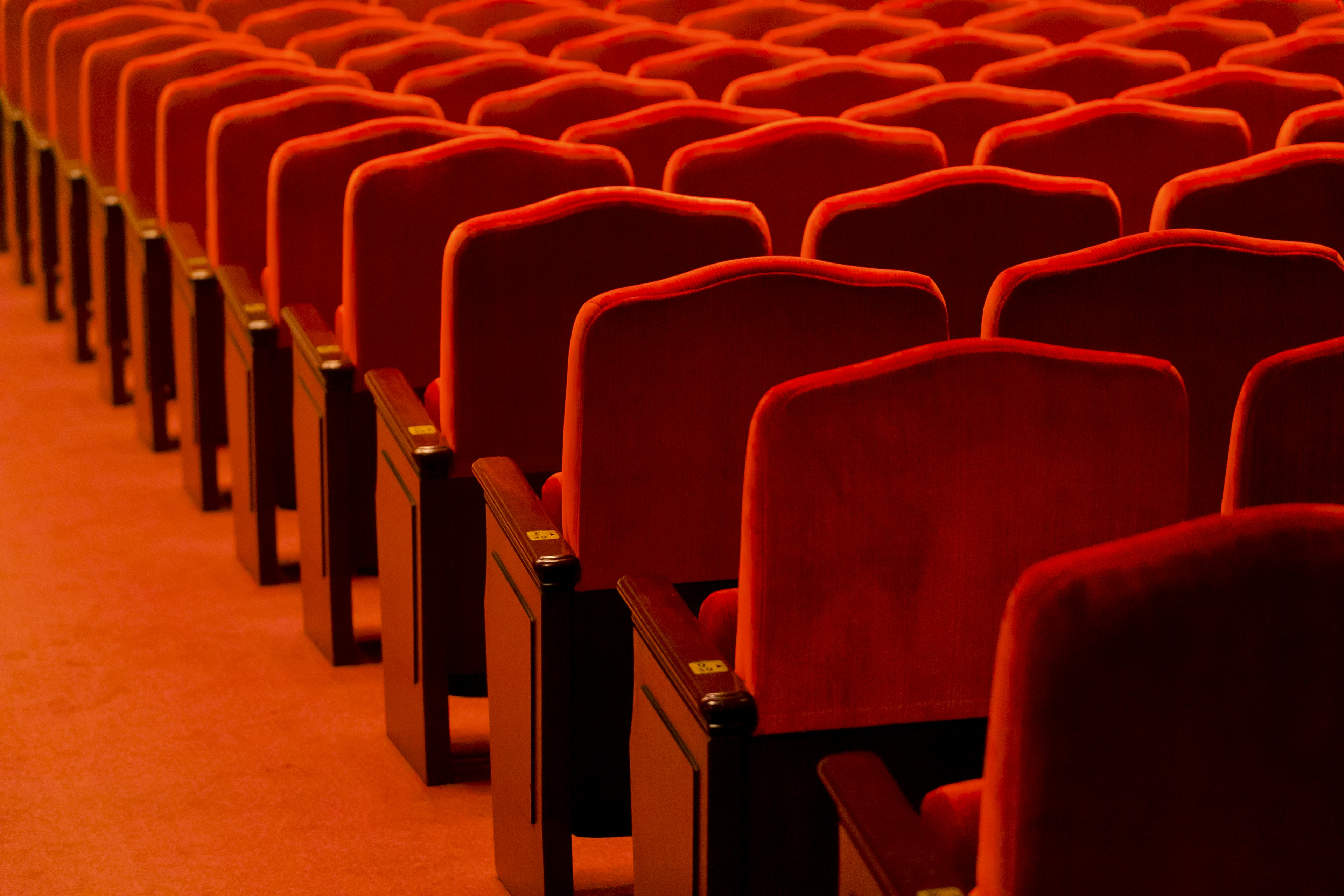 Interior de un teatro con filas de asientos rojos