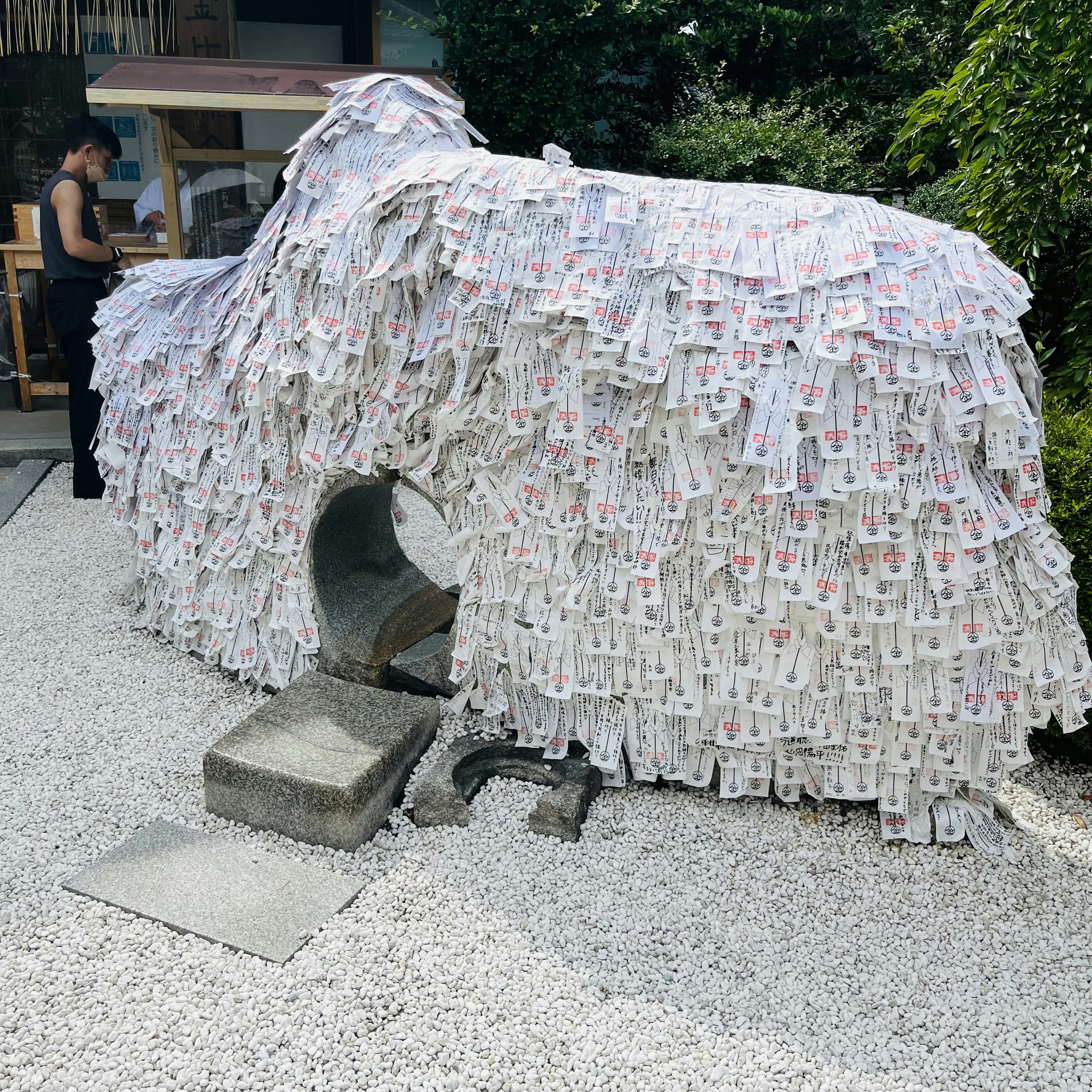 Una escultura en forma de perro cubierta de papeles blancos en un jardín